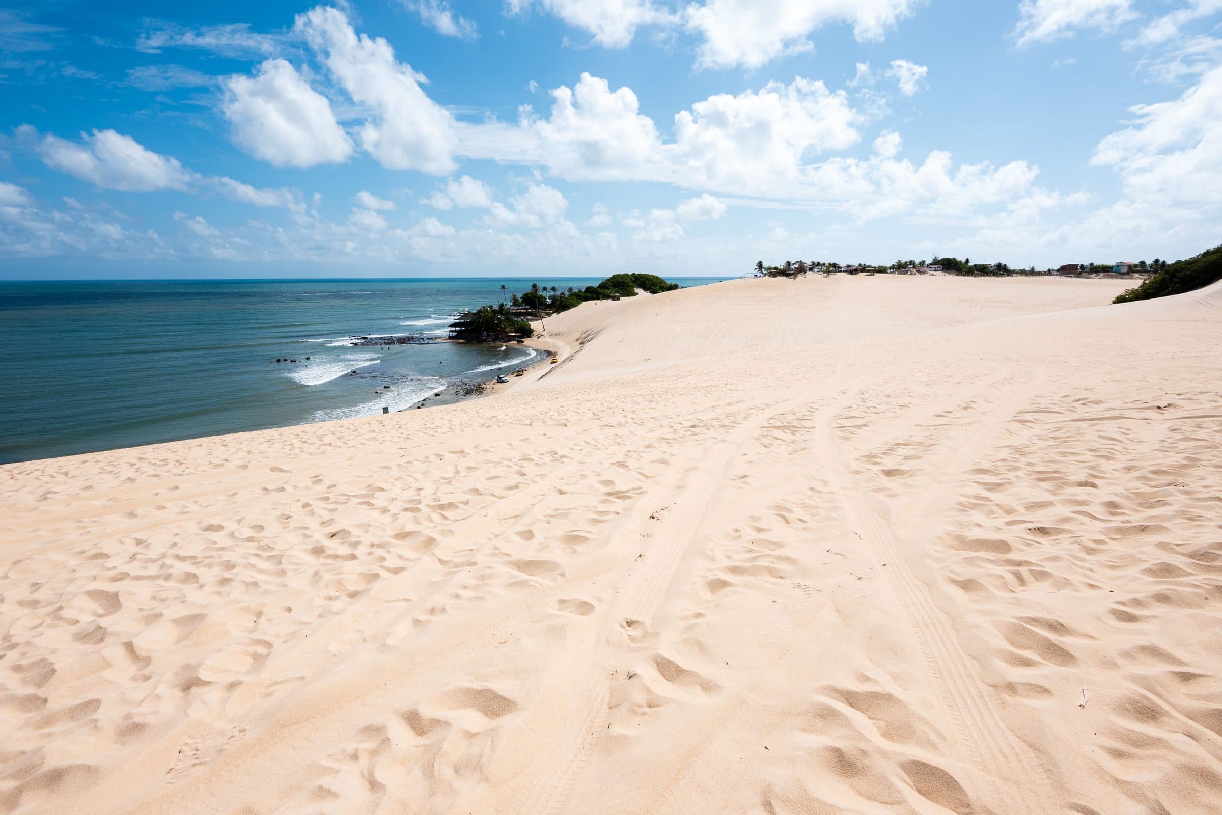 Extensas dunas de areia que levam ao oceano sob um céu azul em Natal