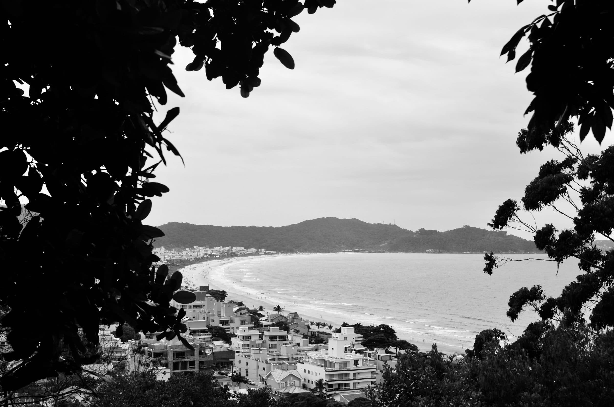 Vista em preto e branco da Praia de Bombinhas cercada por vegetação