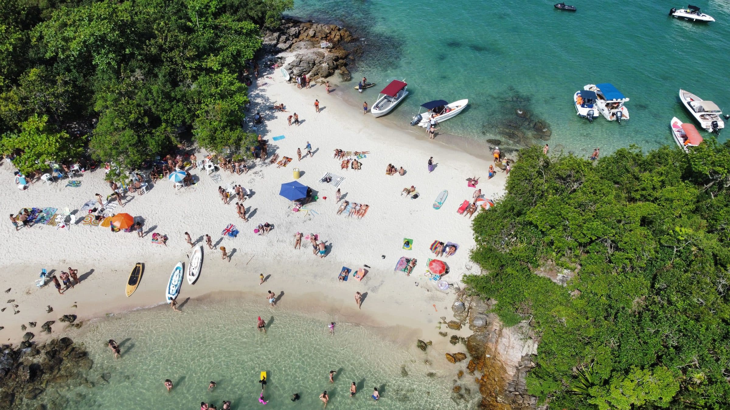 Pessoas aproveitam o dia de verão em uma praia tropical em Angra dos Reis