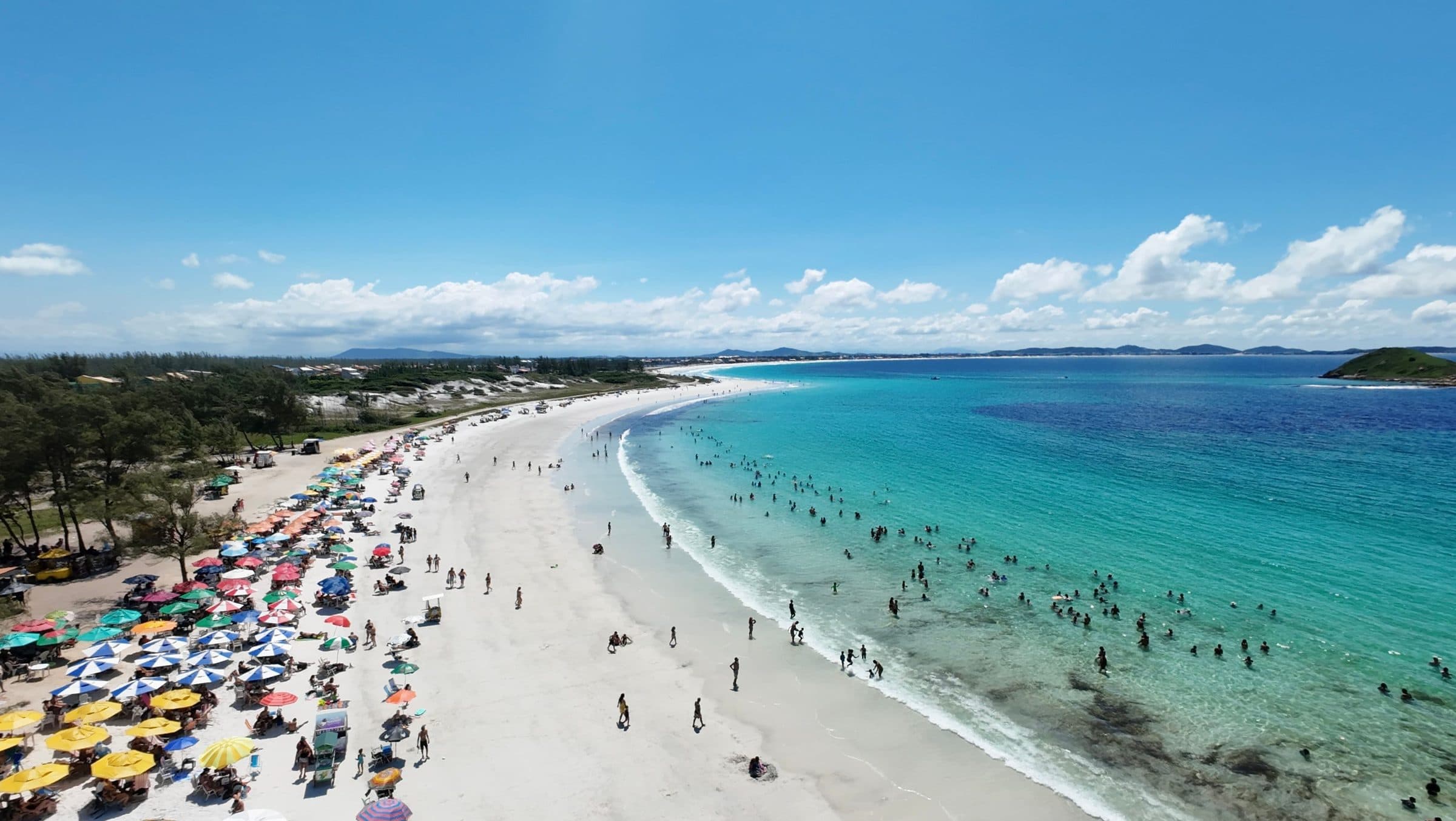 Vista aérea de praia com banhistas e guarda-sóis coloridos na areia