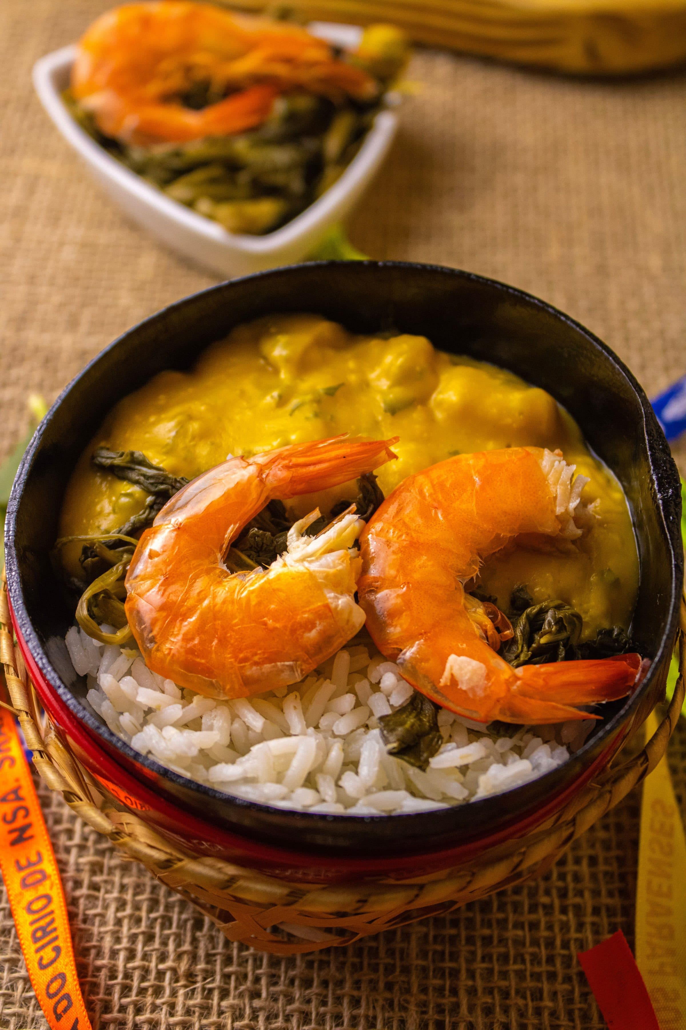 Prato de camarão servido com arroz e folhas verdes em ambiente rústico