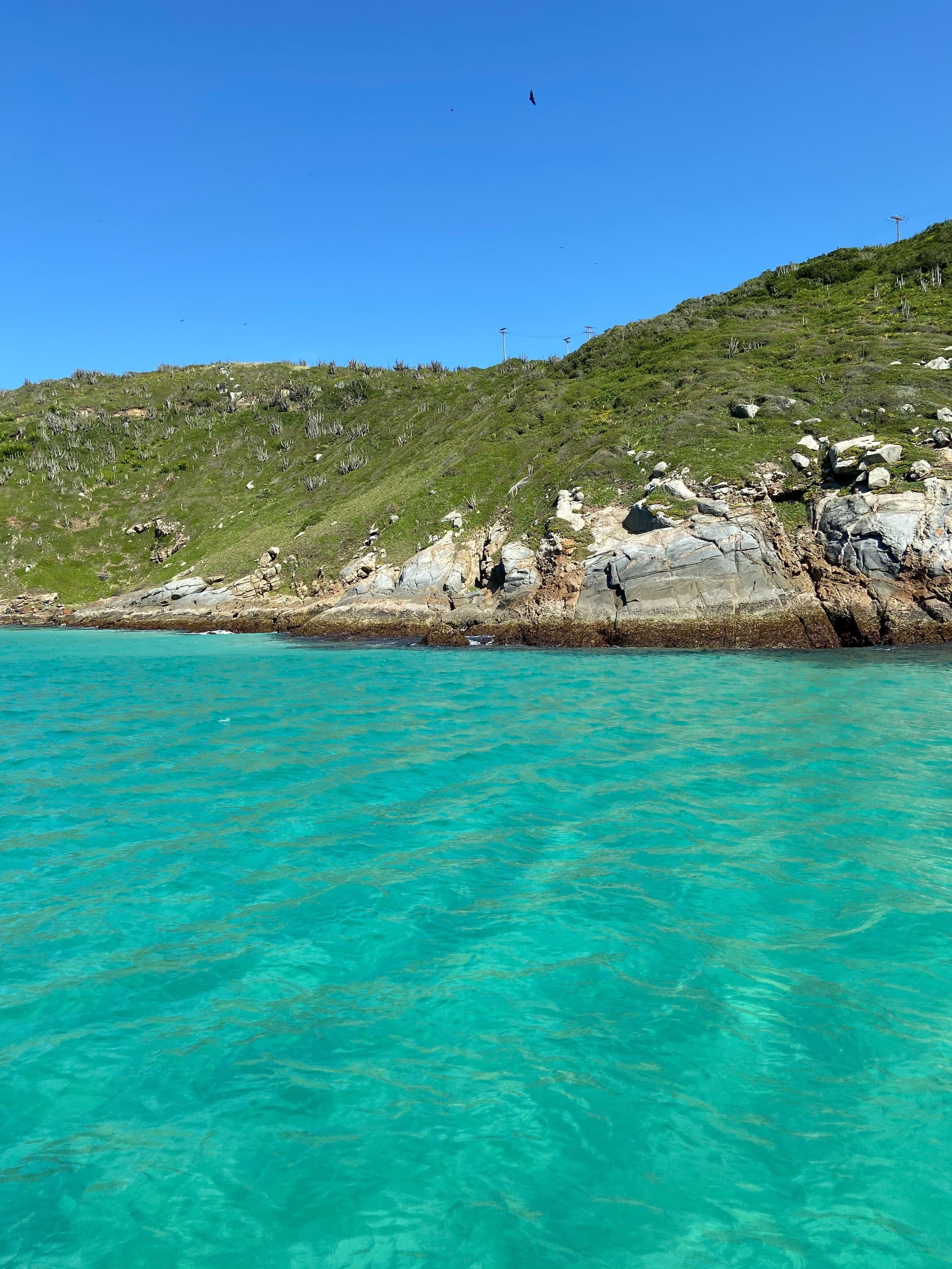 Costa rochosa banhada por águas azul-turquesa em Arraial do Cabo