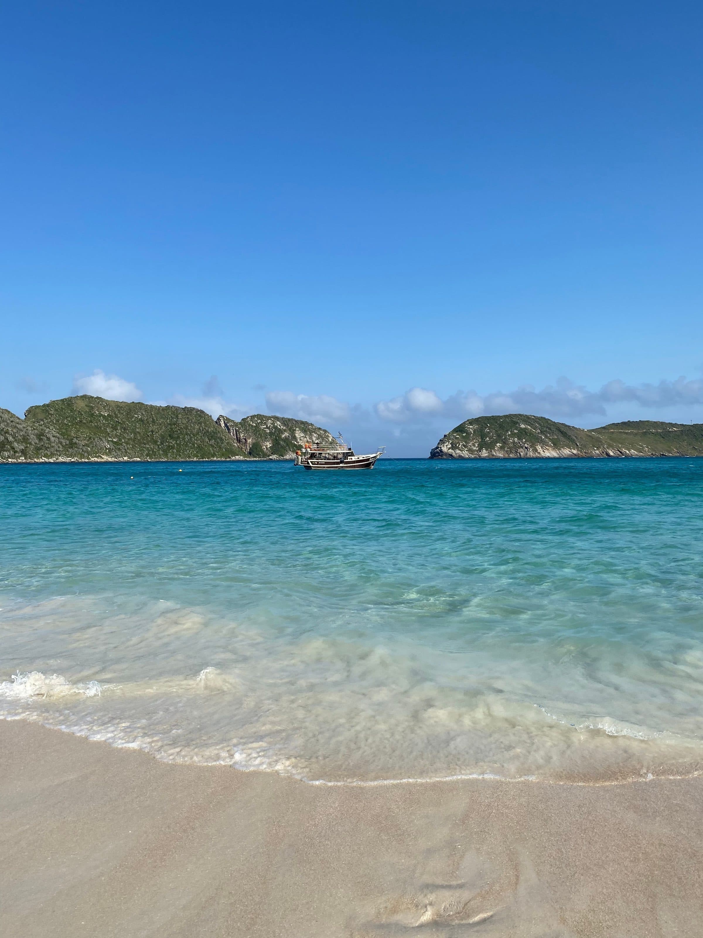 Praia de areia com mar de águas azul-turquesa em Arraial do Cabo