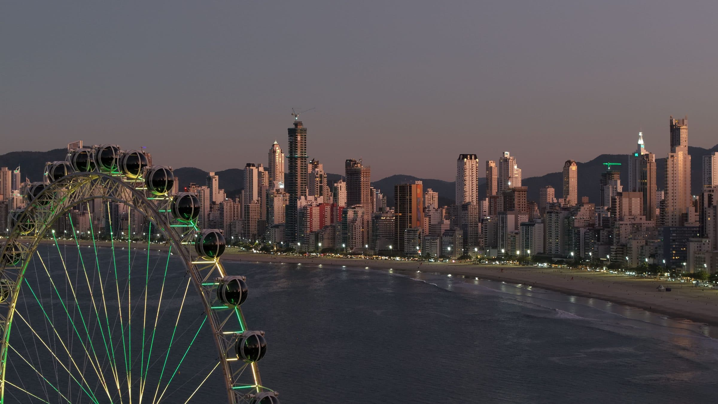 Skyline de Balneário Camboriú com roda-gigante iluminada ao entardecer