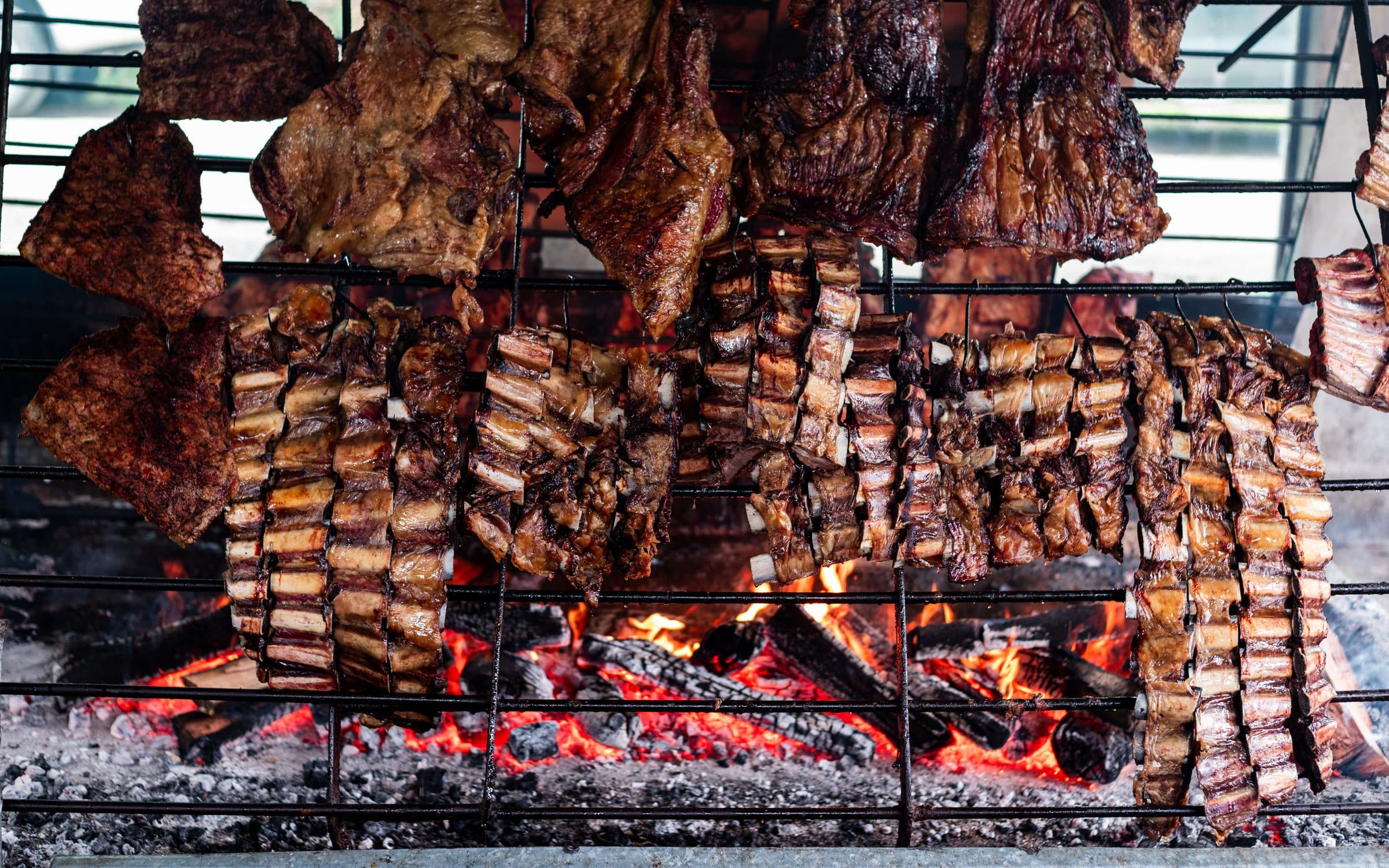 Carnes de assado argentino sendo grelhadas sobre o fogo aberto