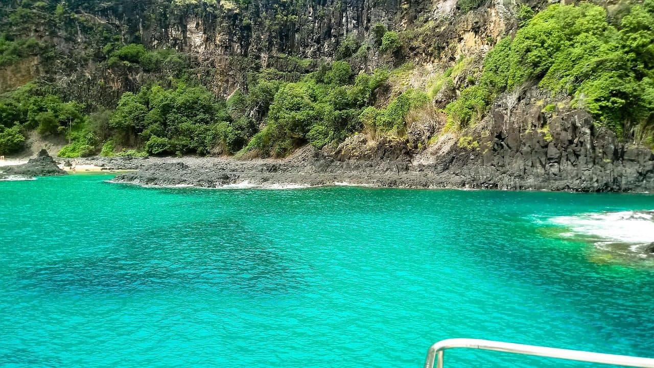 Paisagem de praia e ilha com barco no mar de Fernando de Noronha