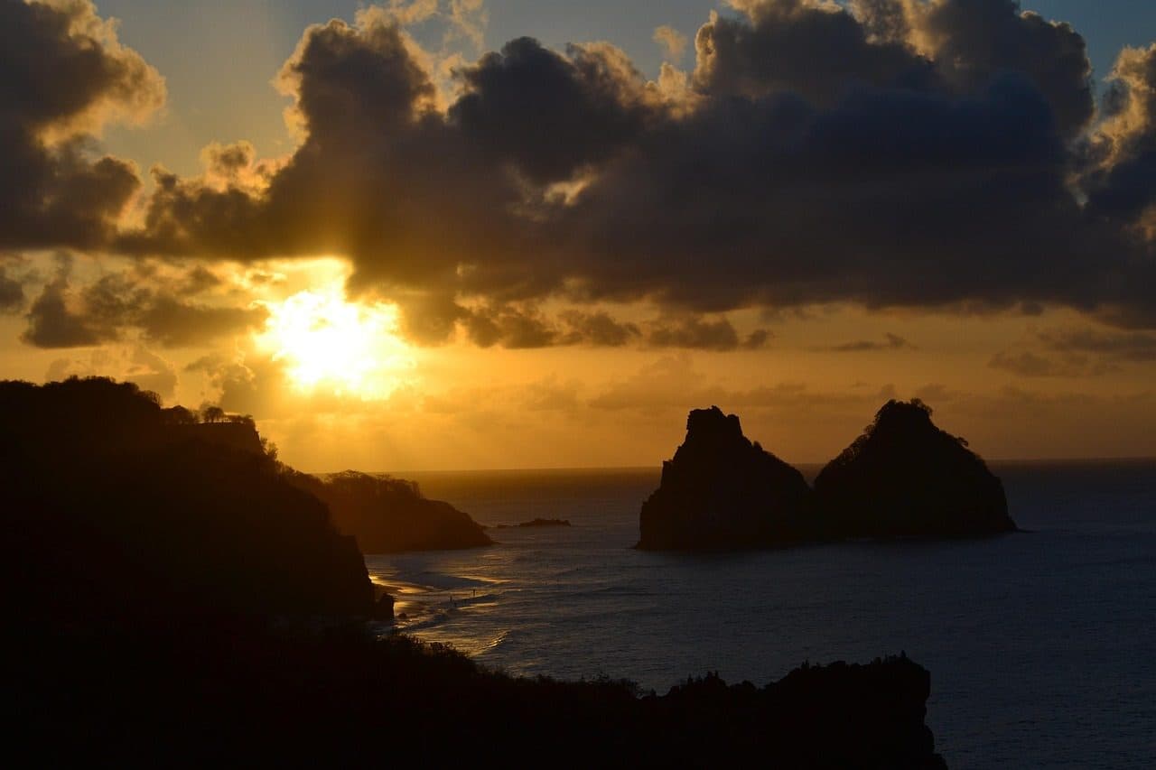 Pôr do sol no mar com vista para a praia em Fernando de Noronha