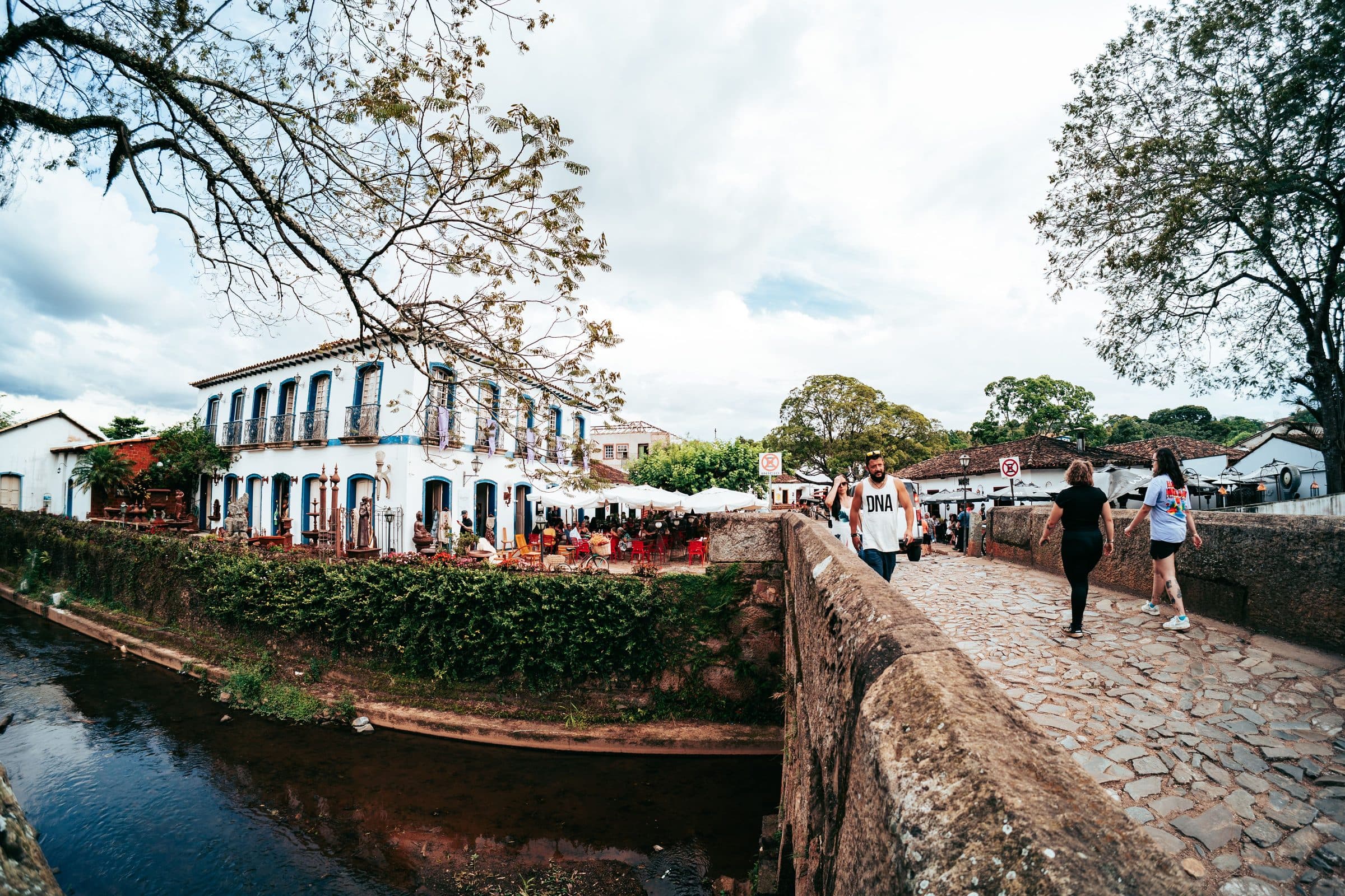 Pessoas caminhando por uma rua de Tiradentes ao lado de um prédio histórico