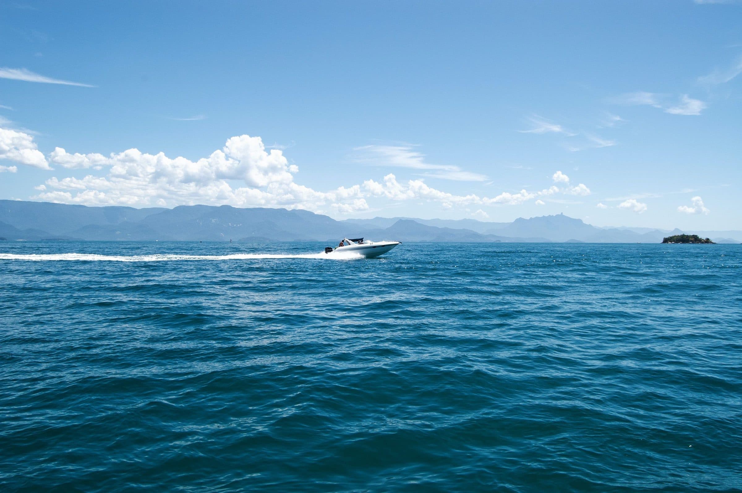 Lancha navegando no mar azul sob céu claro em Paraty