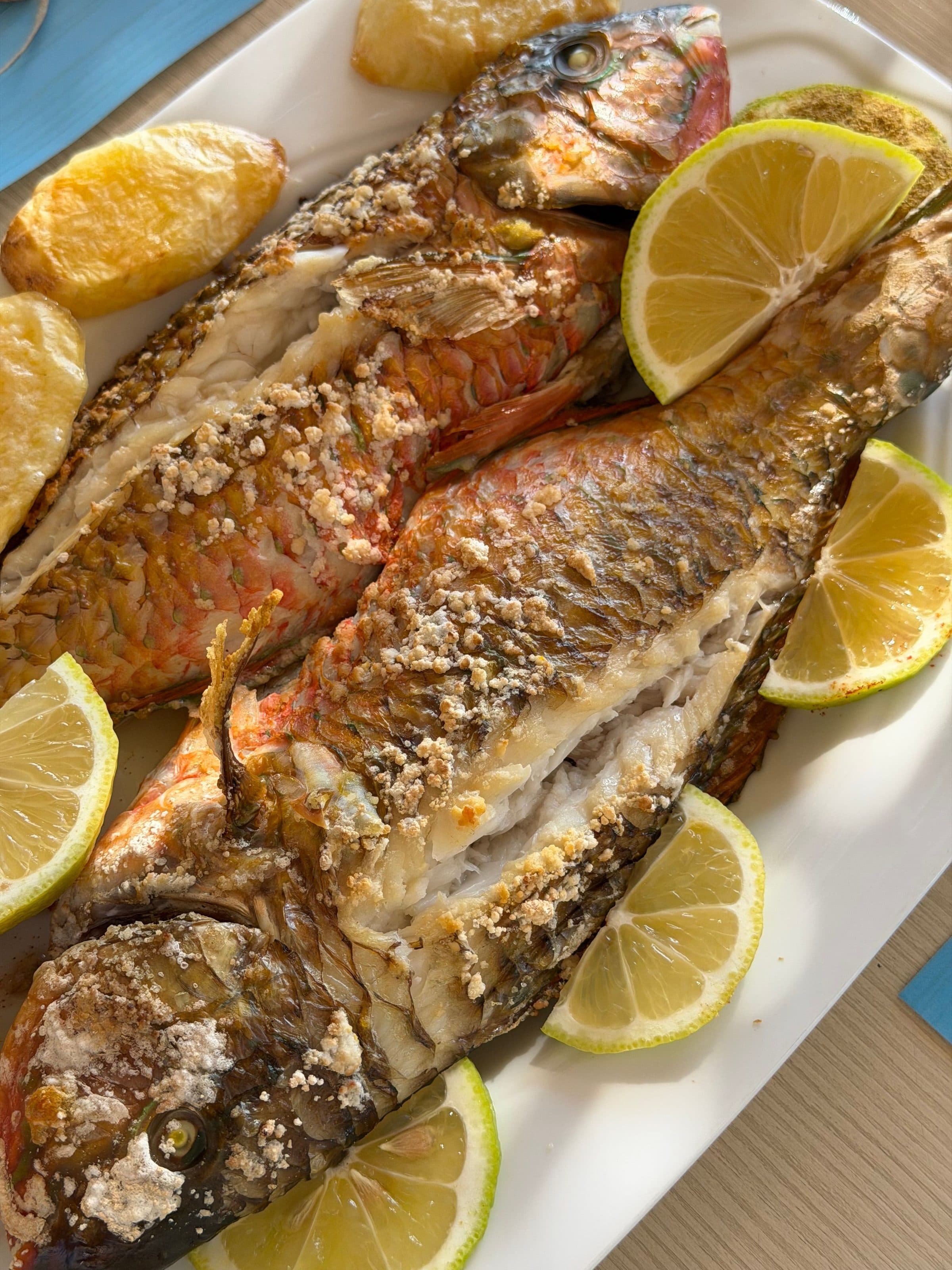 Peixe grelhado servido com rodelas de limão e batatas assadas