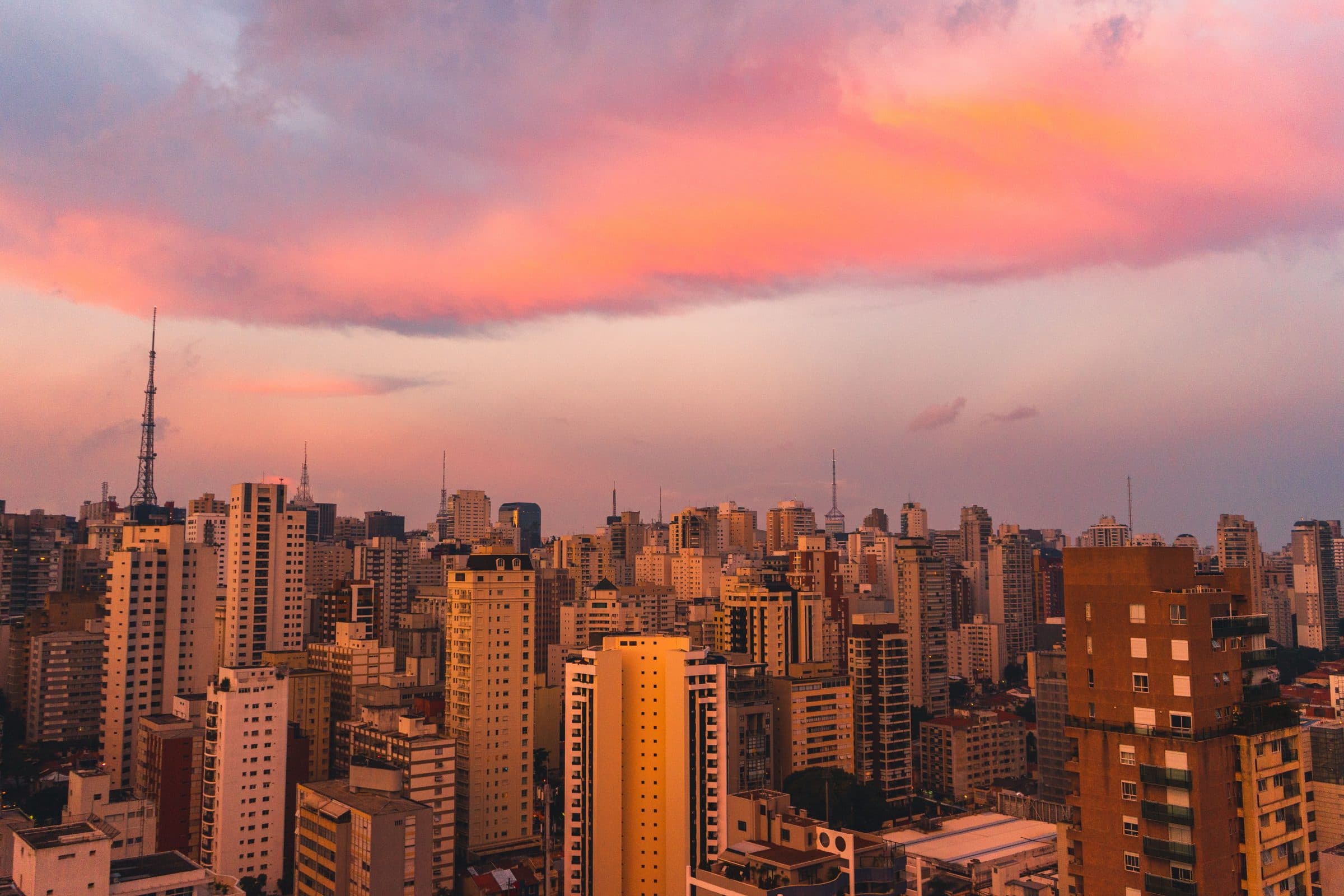 Vista do horizonte de São Paulo ao entardecer com nuvens em tons de rosa e laranja