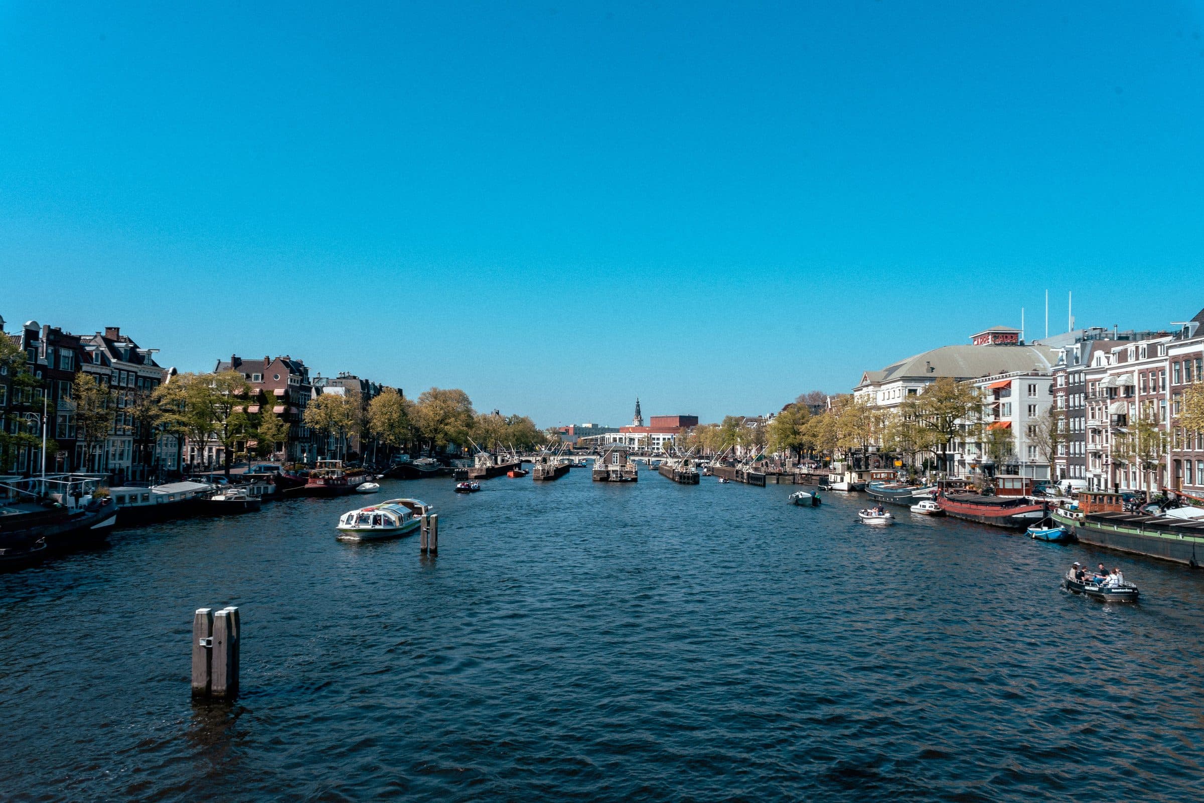 Vista dos canais de Amsterdã com edifícios históricos sob céu azul