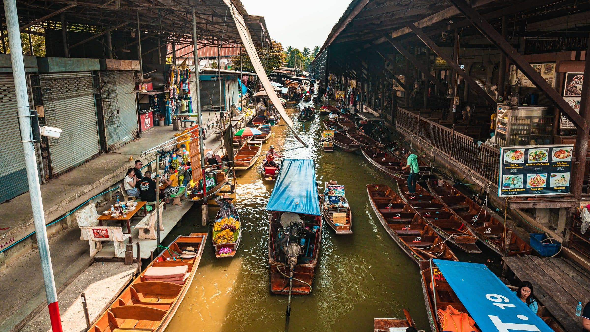 Mercado flutuante em Bangkok com barcos coloridos e vendedores ao longo do canal