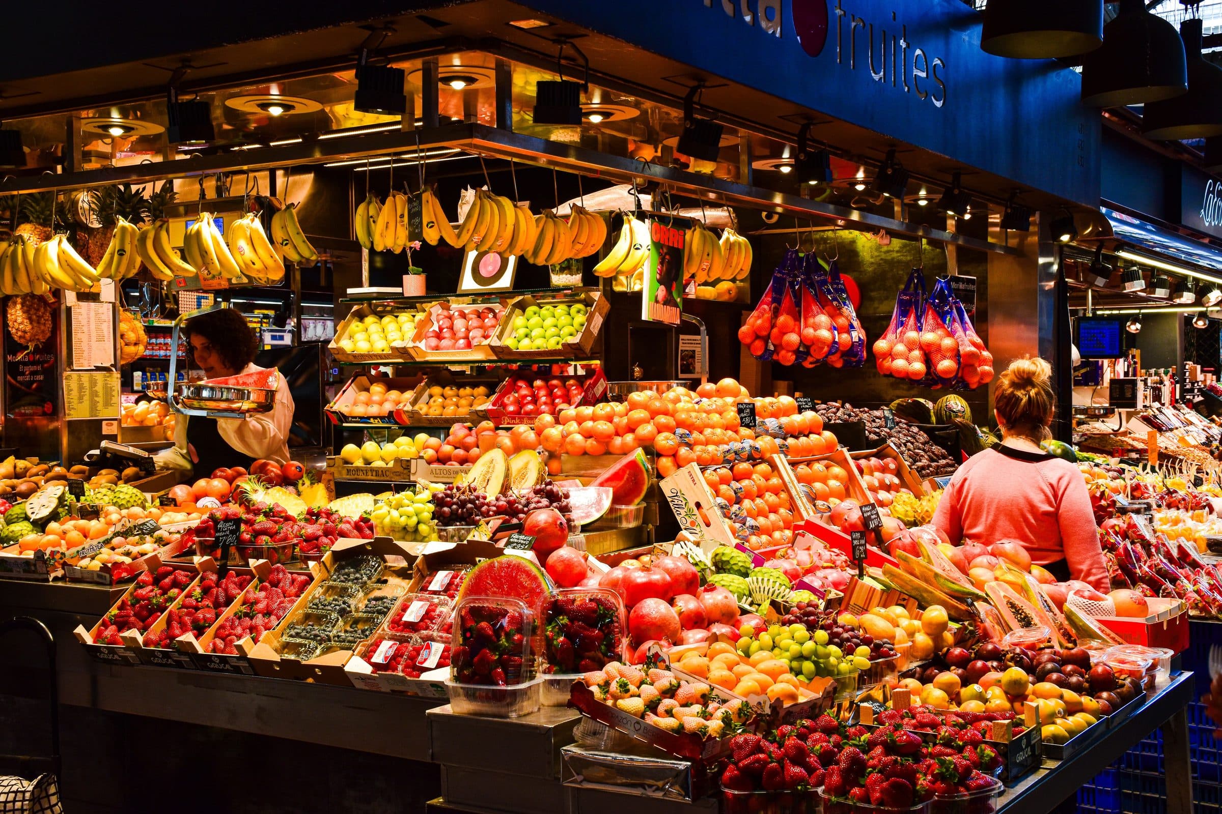 Banca com frutas coloridas expostas em mercado movimentado de Barcelona, Espanha