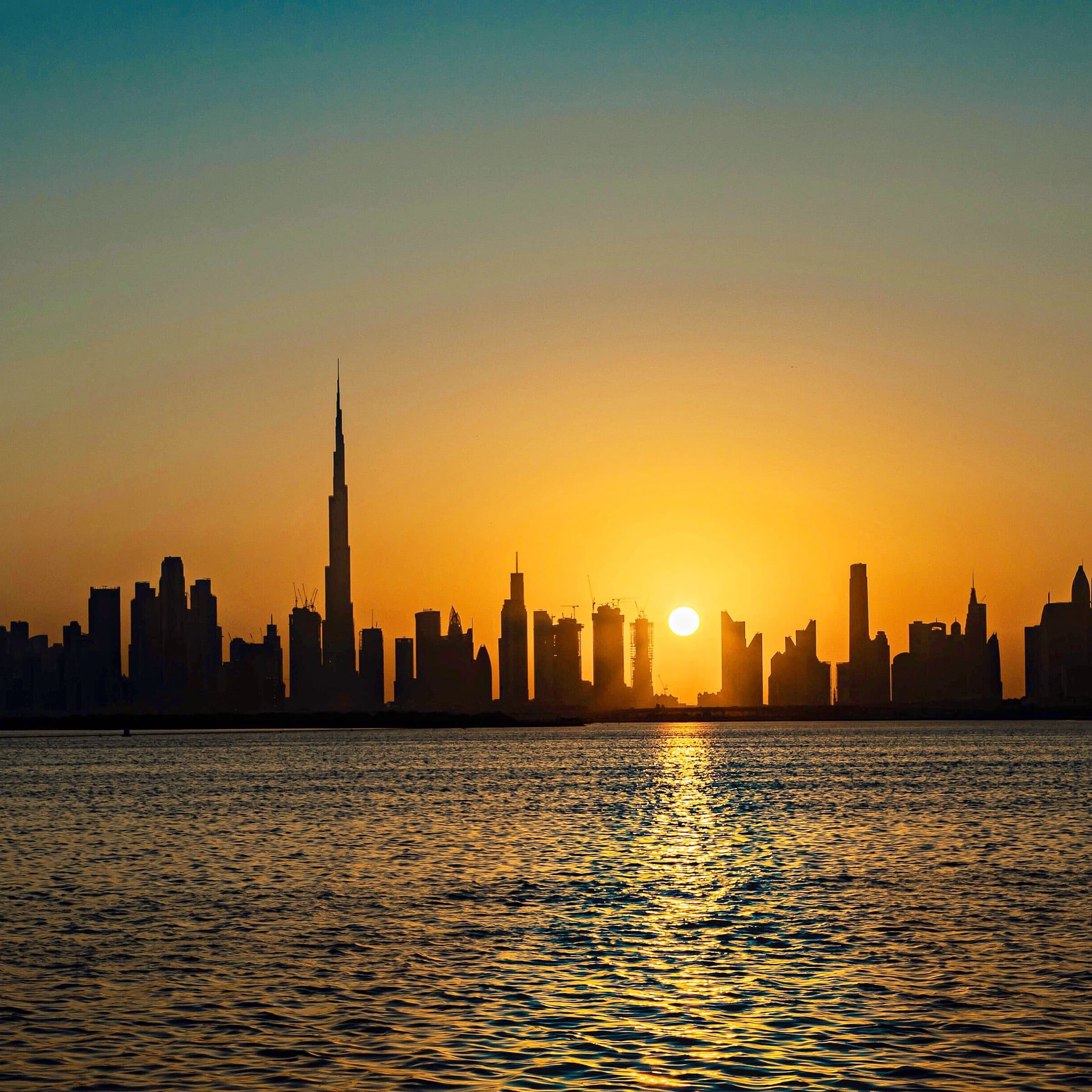 Silhueta dos arranha-céus de Dubai ao pôr do sol com reflexos na água