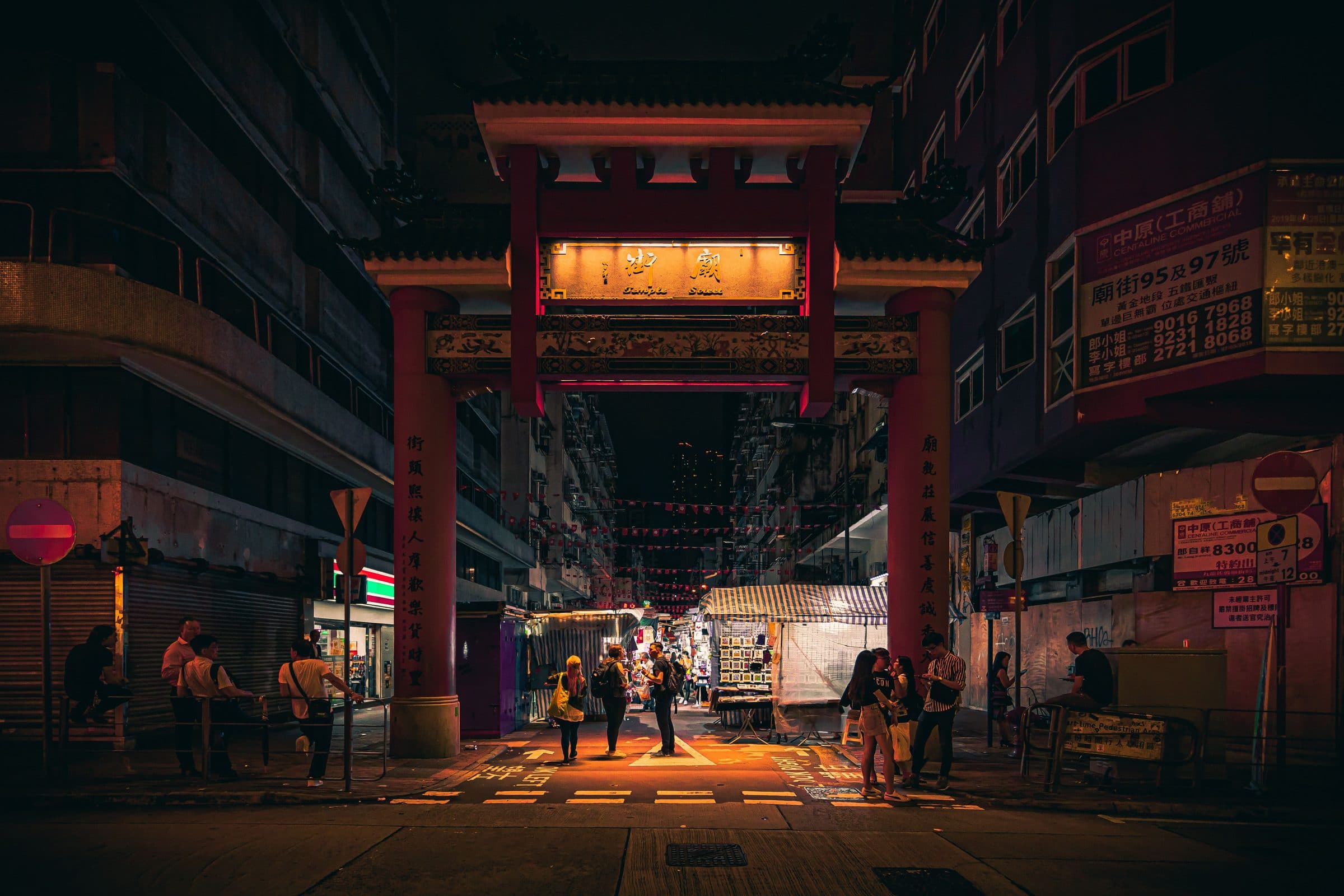 Pessoas circulando sob luzes brilhantes no Mercado Noturno de Temple Street em Hong Kong