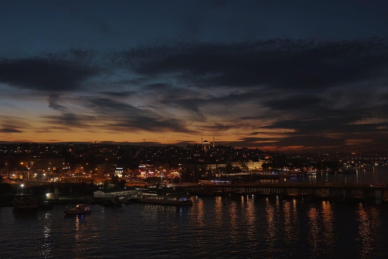 Vista noturna de Istambul com edifícios iluminados à beira do mar