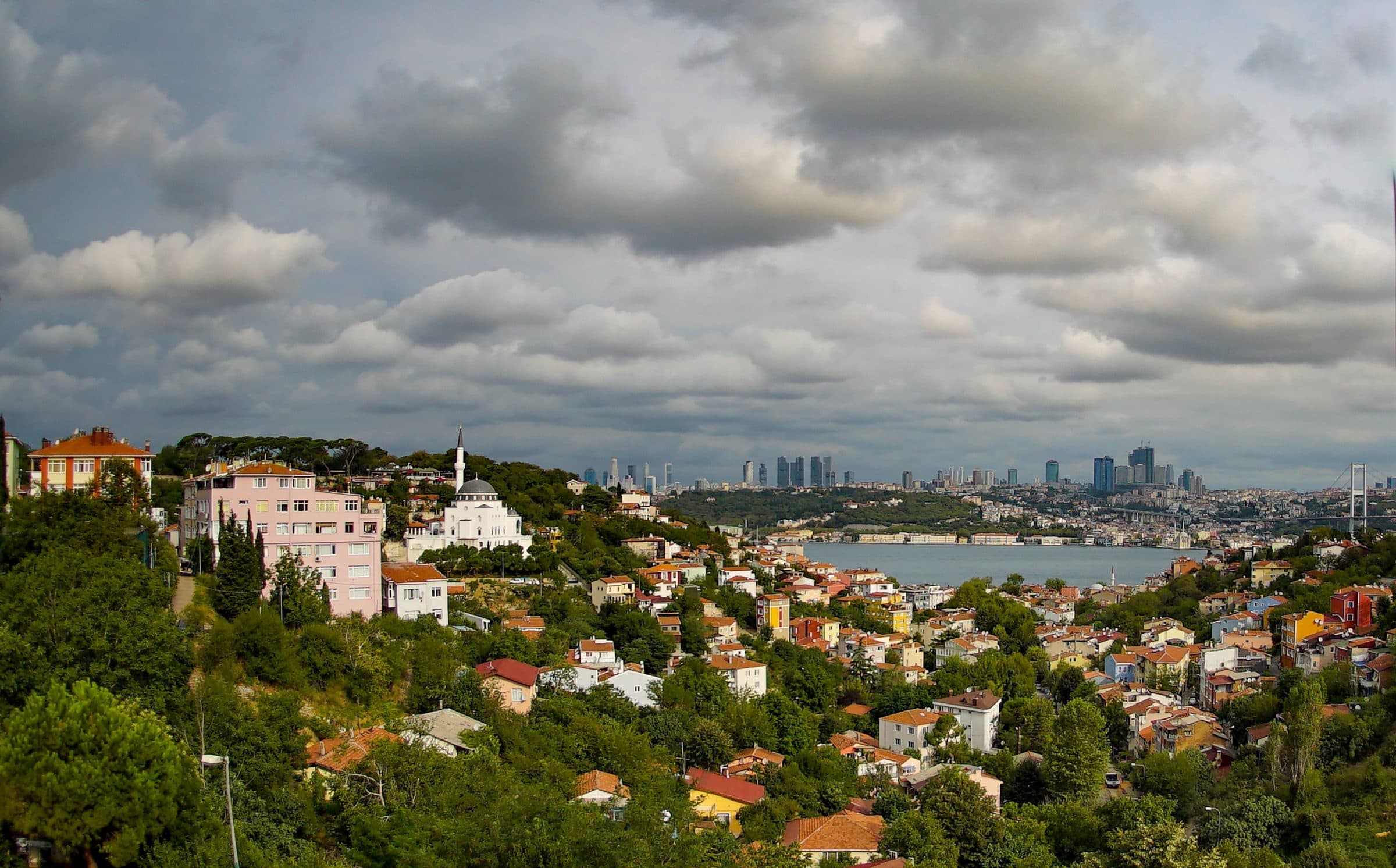 Vista aérea de Istambul com prédios coloridos, vegetação e o Bósforo sob céu nublado