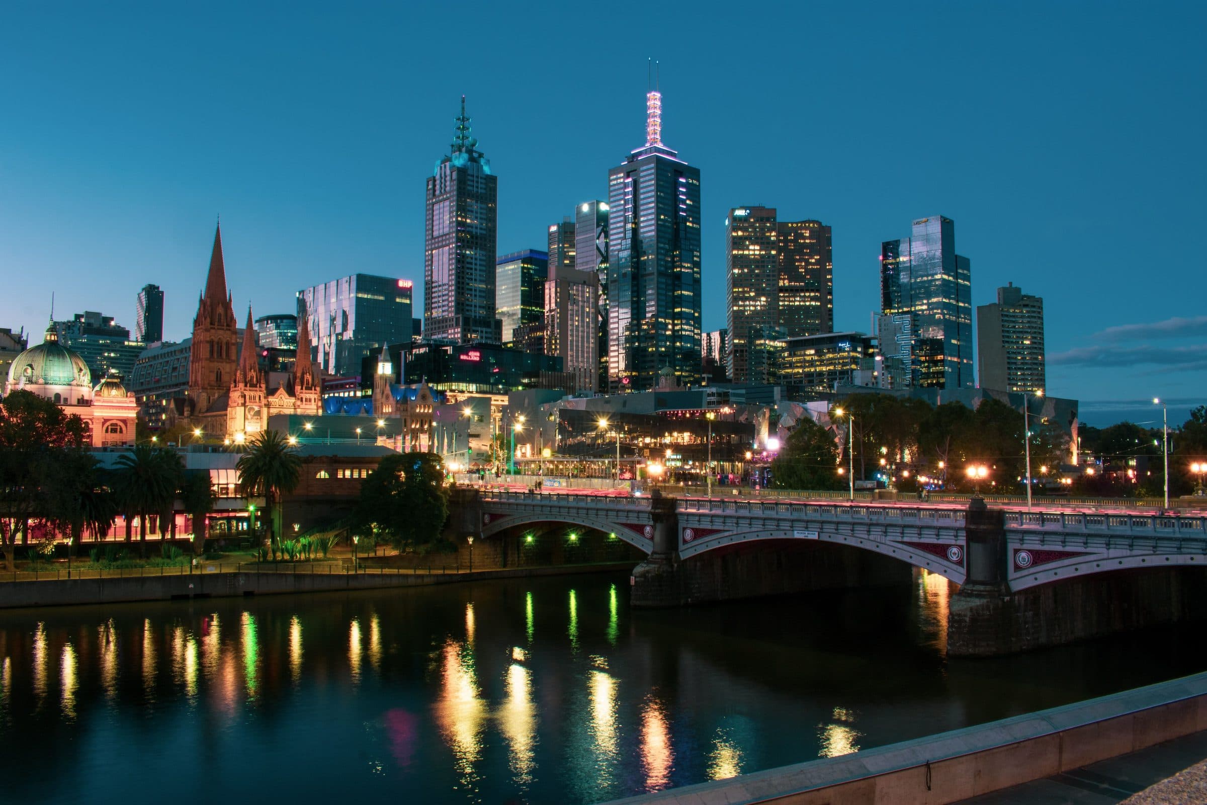 Edifícios de Melbourne e a Princes Bridge refletidos no Yarra River durante o entardecer