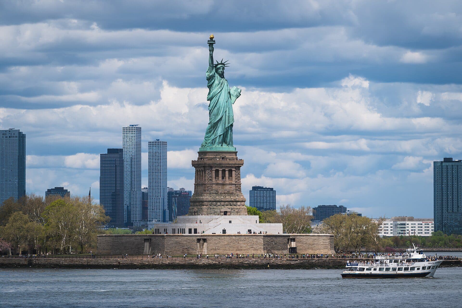 Estátua da Liberdade com barco de passeio turístico em Liberty Island, New York