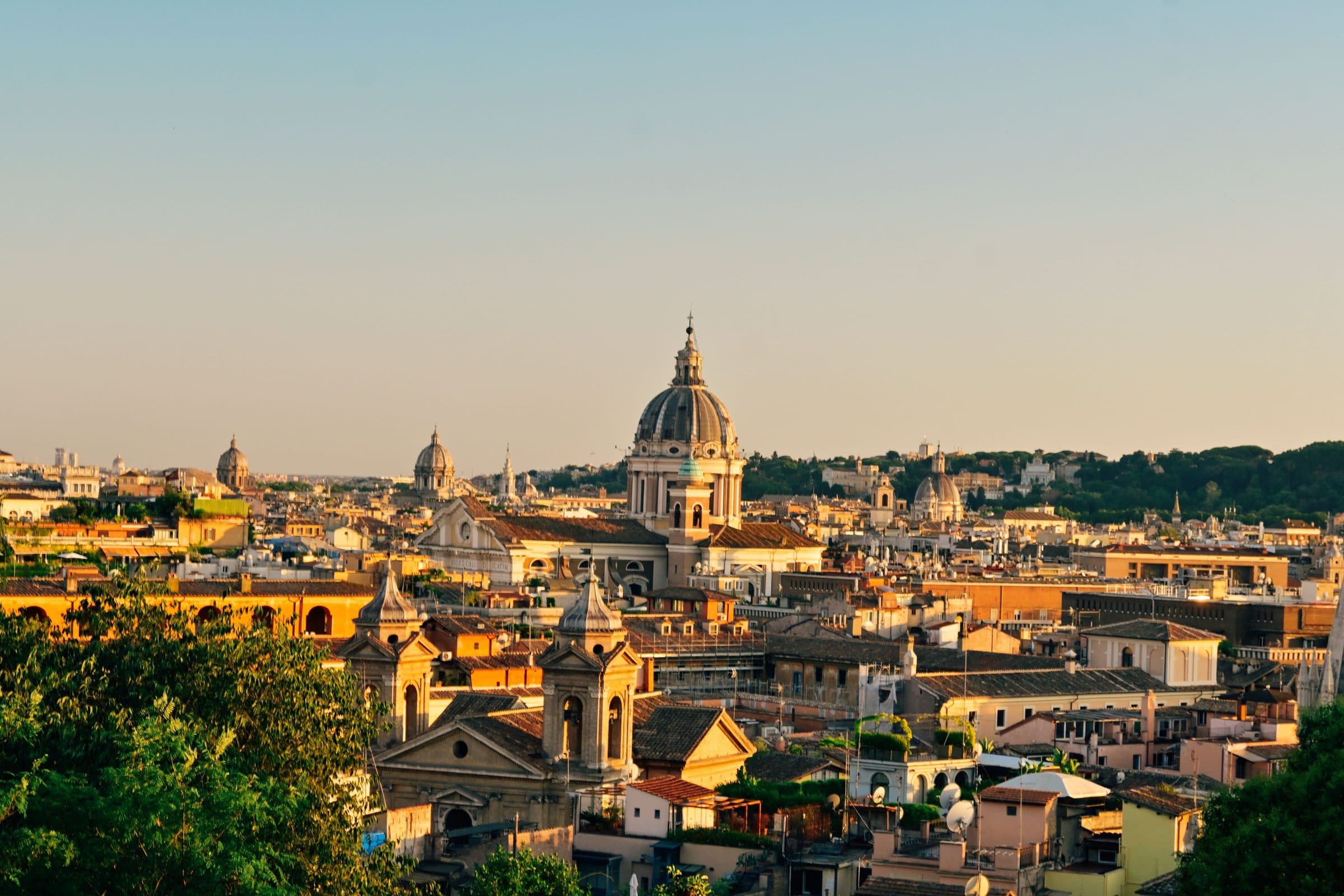 Vista panorâmica de Roma ao pôr do sol com cúpulas e edifícios históricos