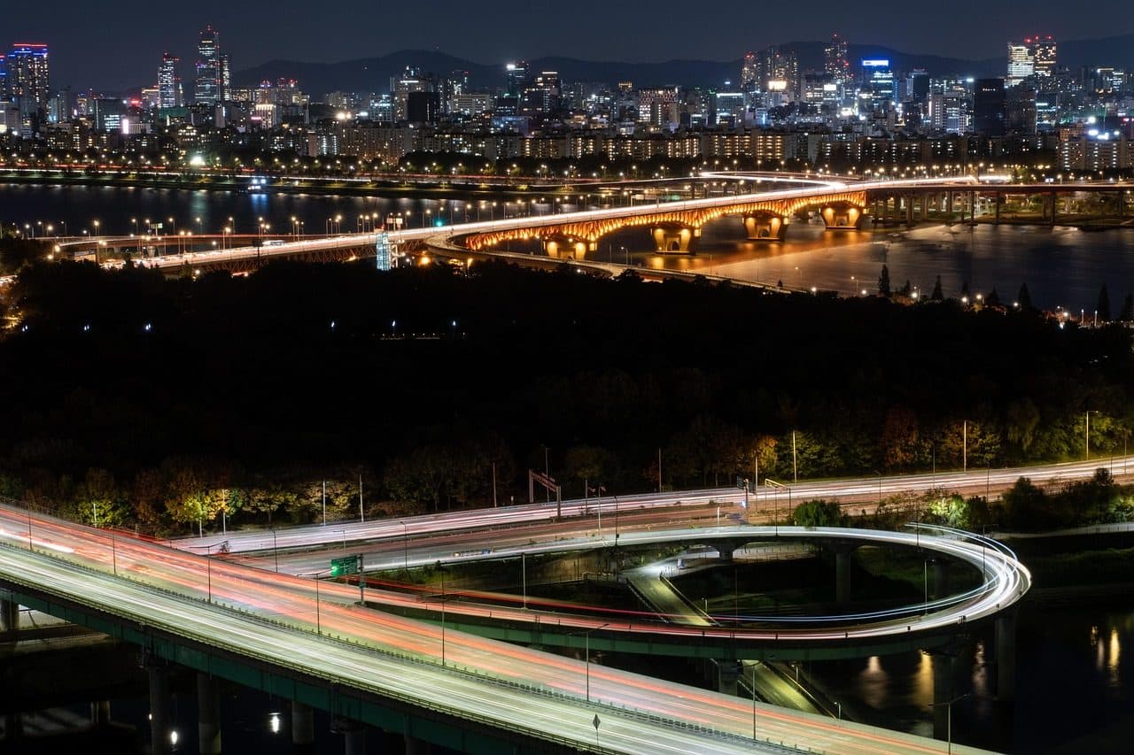 Vista noturna de Seul com ponte sobre o rio, prédios e vias iluminadas