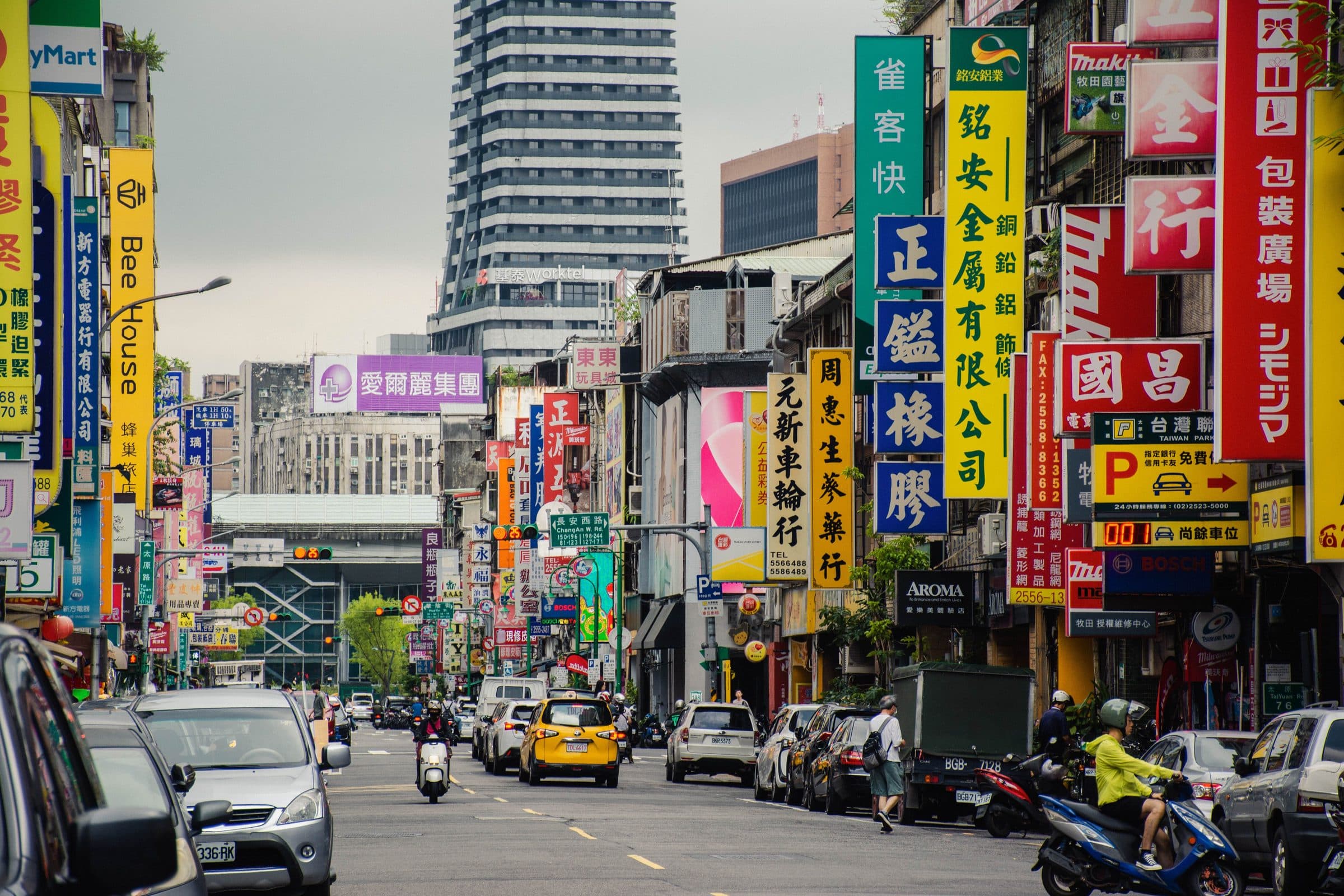 Rua movimentada em Taipei com letreiros coloridos e trânsito intenso