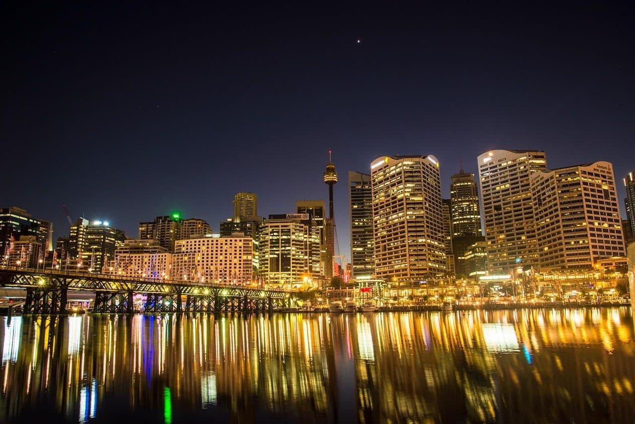 Vista noturna de Darling Harbour em Sydney com arranha-céus iluminados refletidos na água