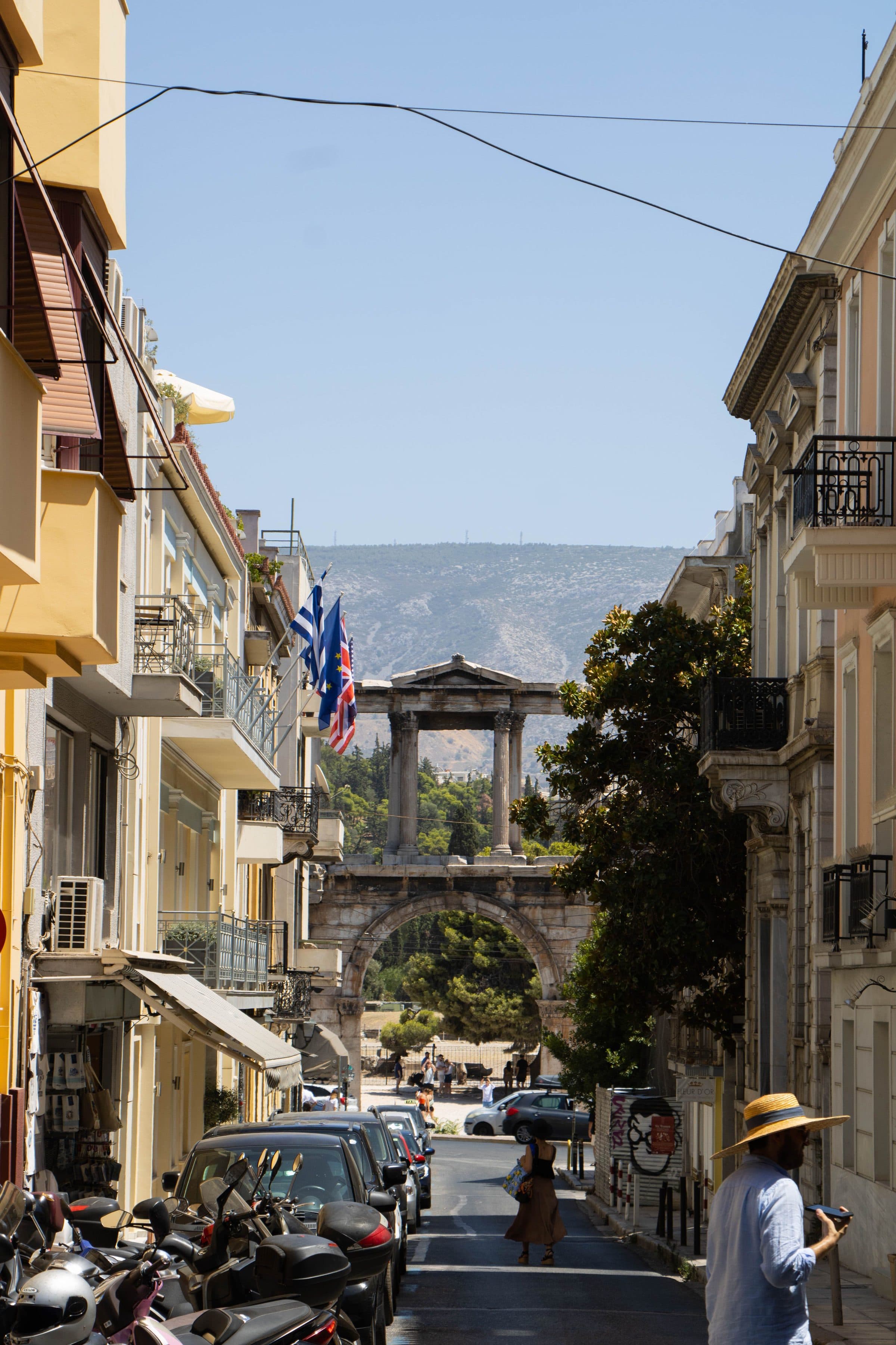Vista do Arco de Adriano emoldurado por uma rua da cidade de Atenas