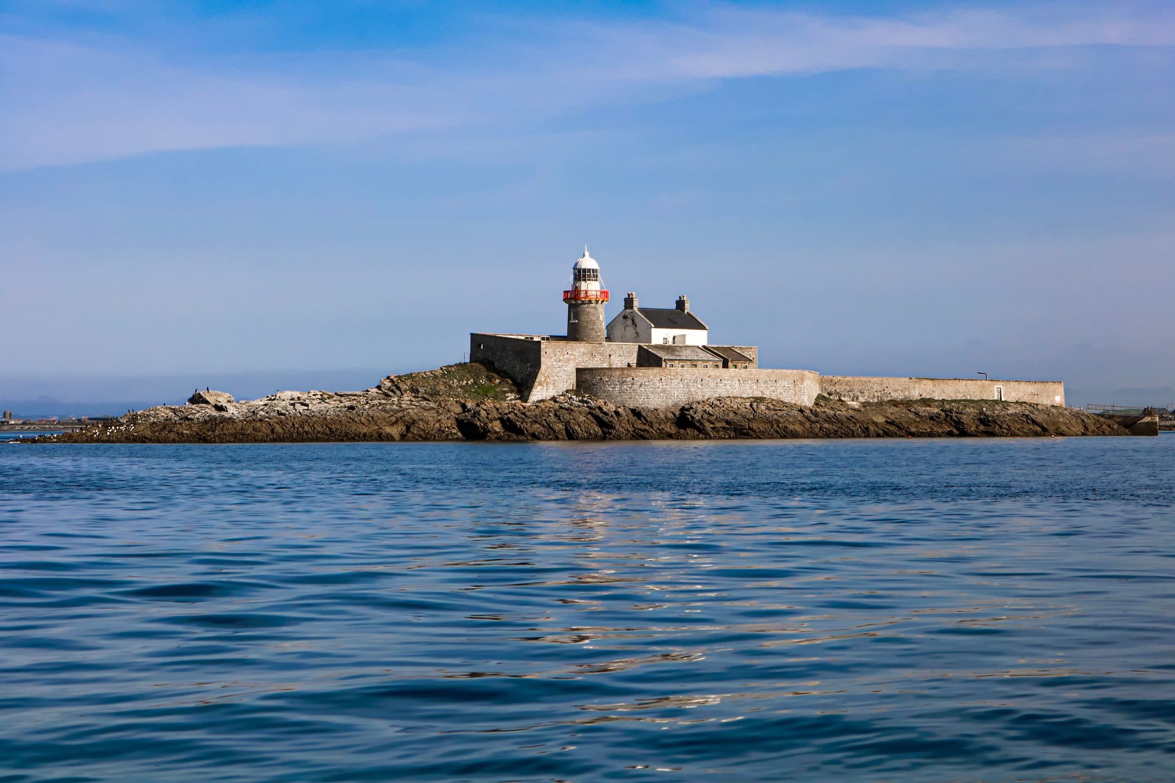 Farol Fenit na Little Samphire Island, cercado por mar calmo na Irlanda