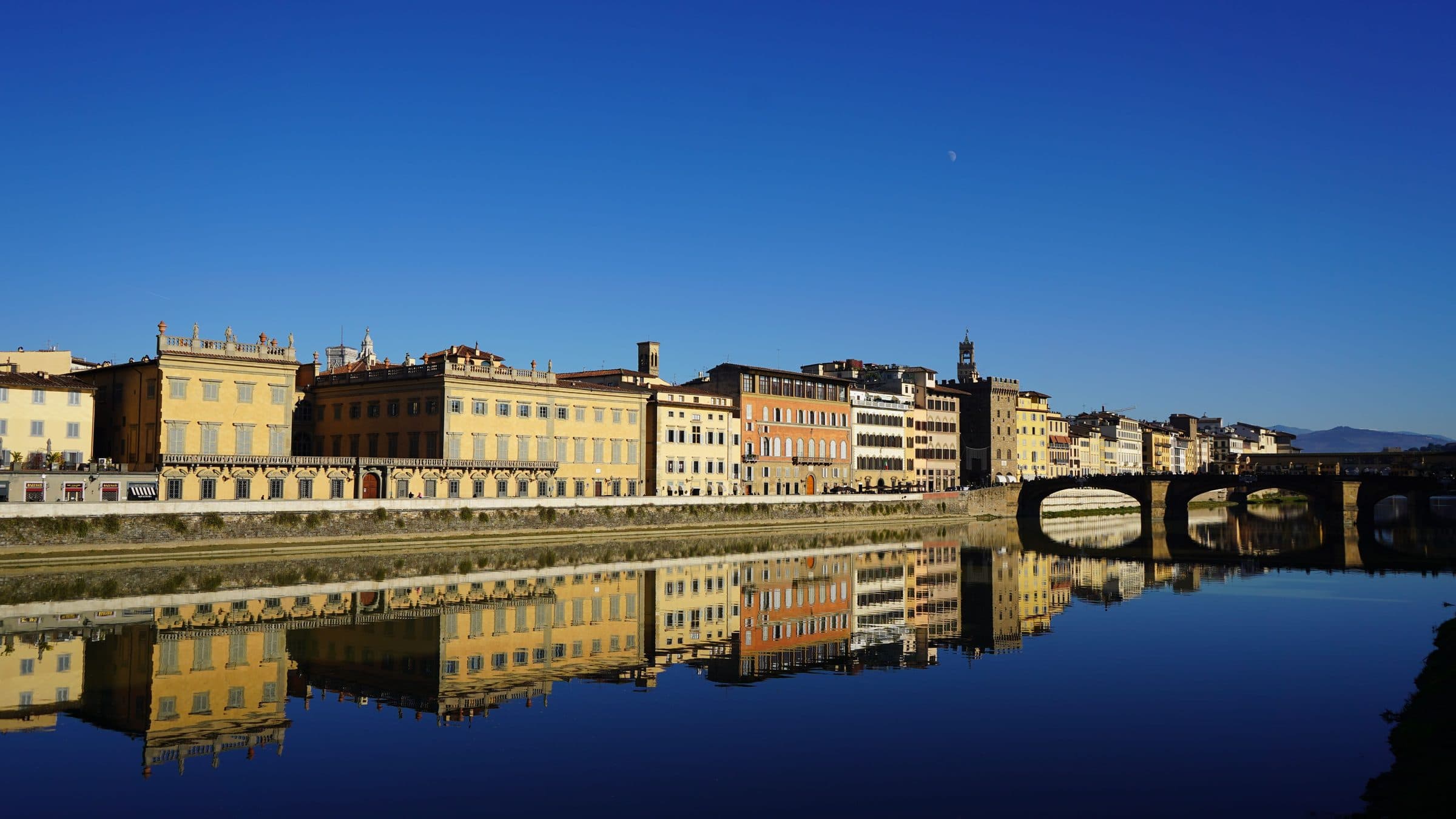 Reflexo de edifícios de Florença nas águas do Rio Arno sob céu azul