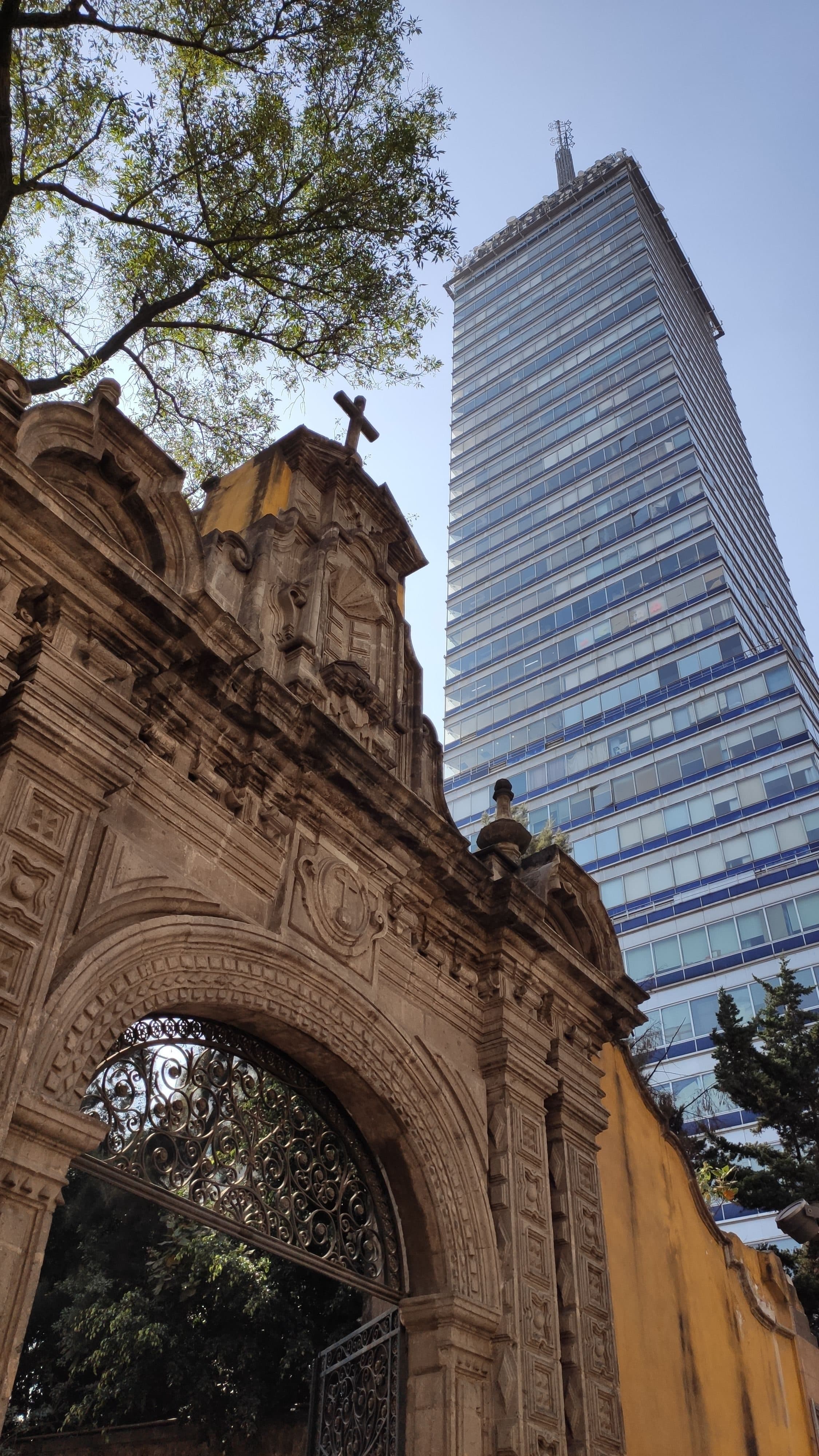 Entrada de igreja histórica em contraste com arranha-céu moderno em Ciudad de México