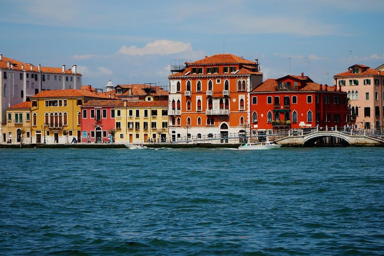 Casas coloridas e barcos ao longo de um canal com ponte na ilha de Giudecca, em Veneza
