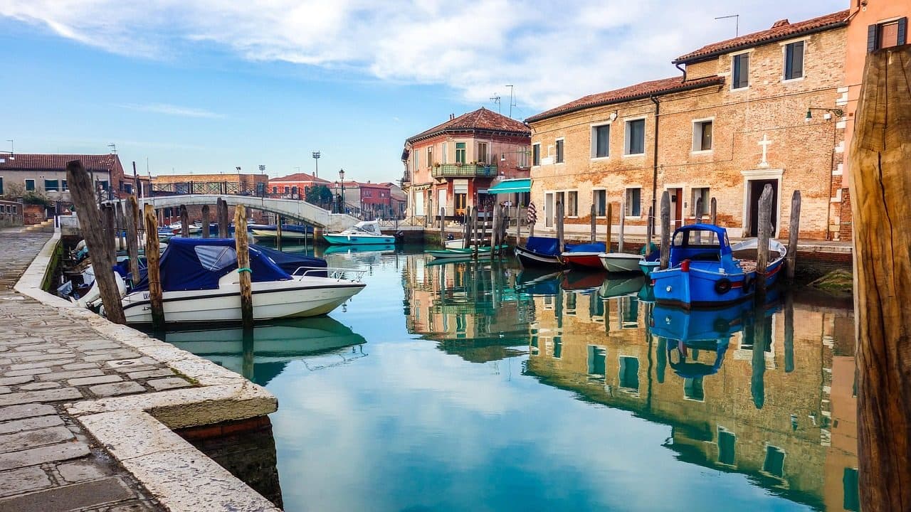 Casas coloridas e barcos às margens de um canal na Ilha de Murano, em Veneza