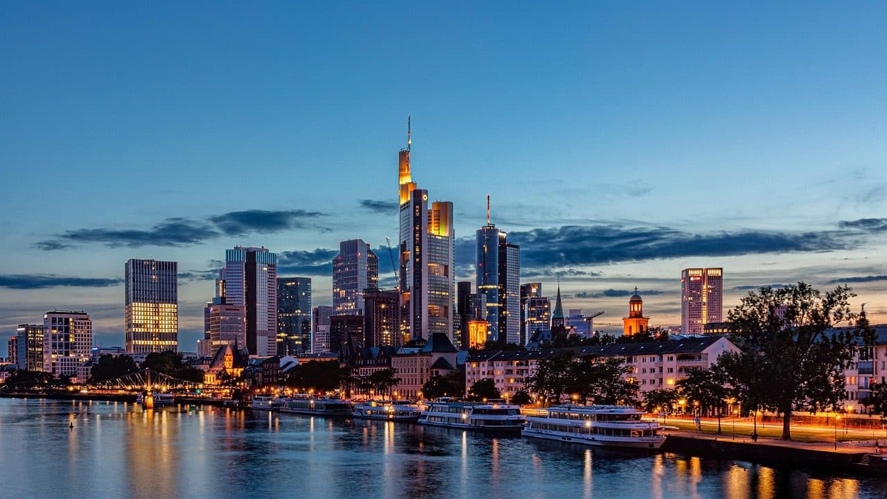 Skyline de Frankfurt am Main com arranha-céus iluminados à beira da água ao entardecer
