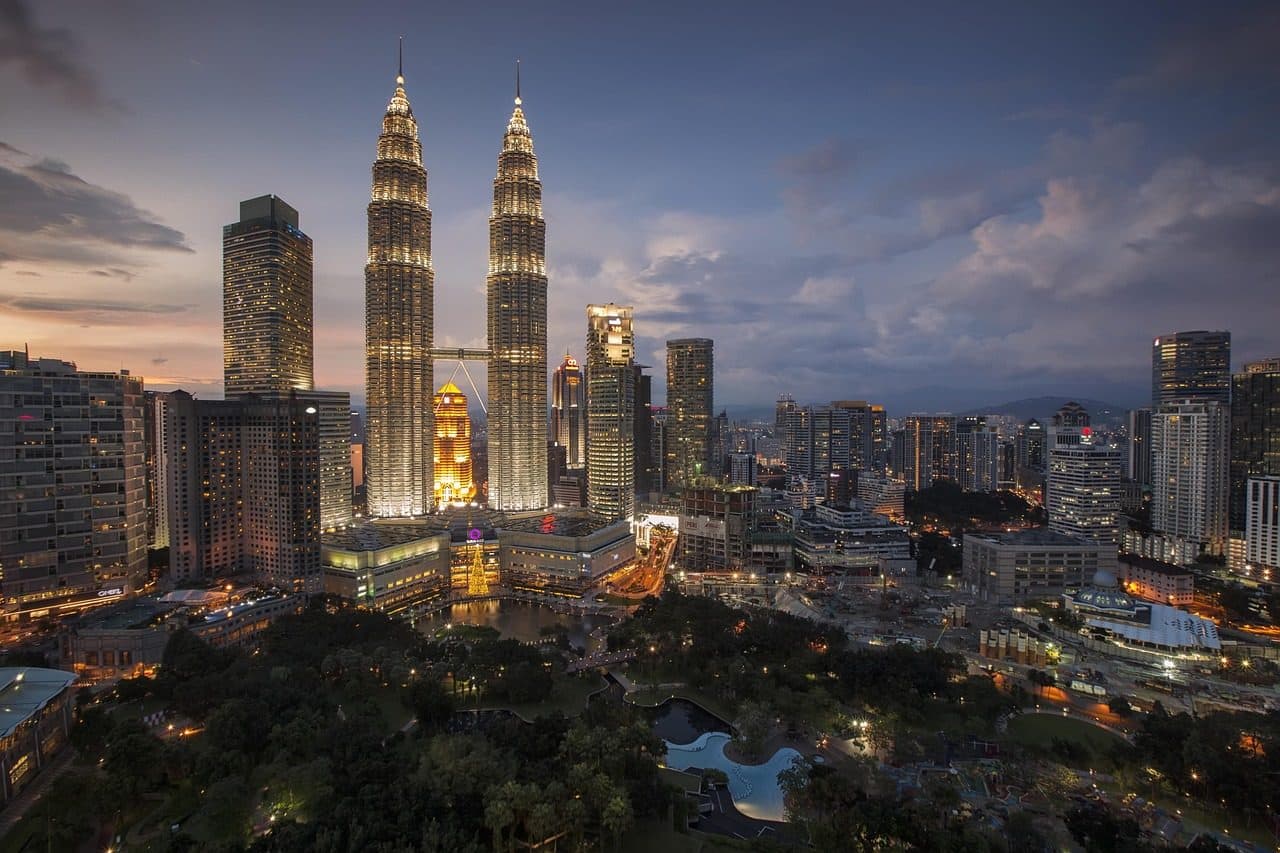 Panorama urbano de Kuala Lumpur com as Torres Gêmeas e prédios iluminados ao entardecer