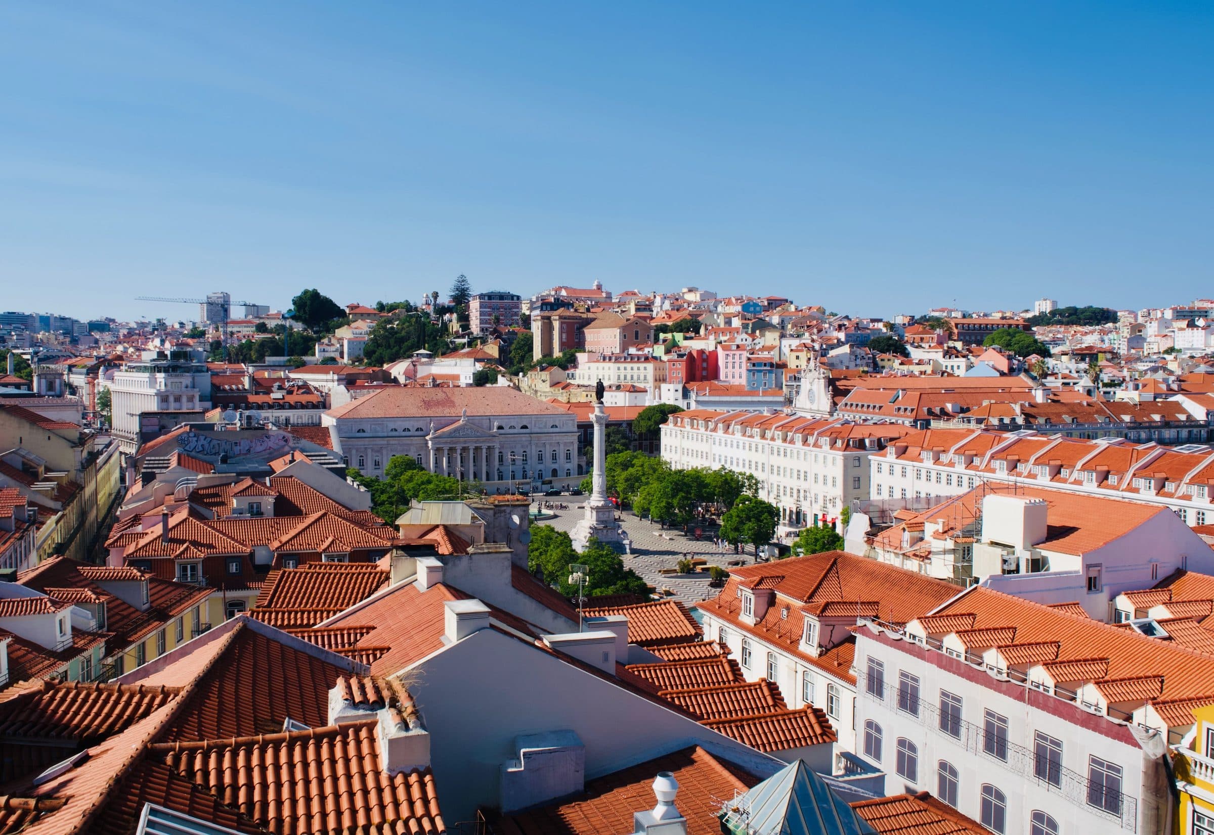 Vista aérea do centro histórico de Lisboa com telhados vermelhos sob céu azul