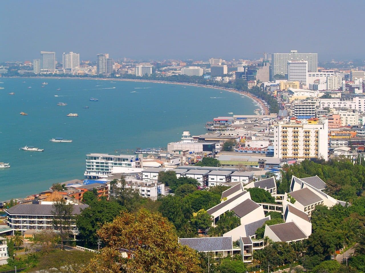 Vista da baía de Pattaya na Tailândia, com praia de águas claras, barcos e edifícios à beira-mar