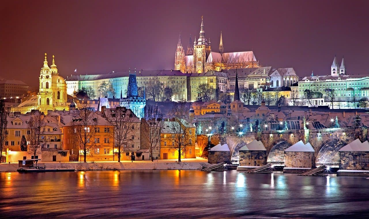 Vista noturna de Praga no inverno com o Castelo de Praga e a Charles Bridge iluminados