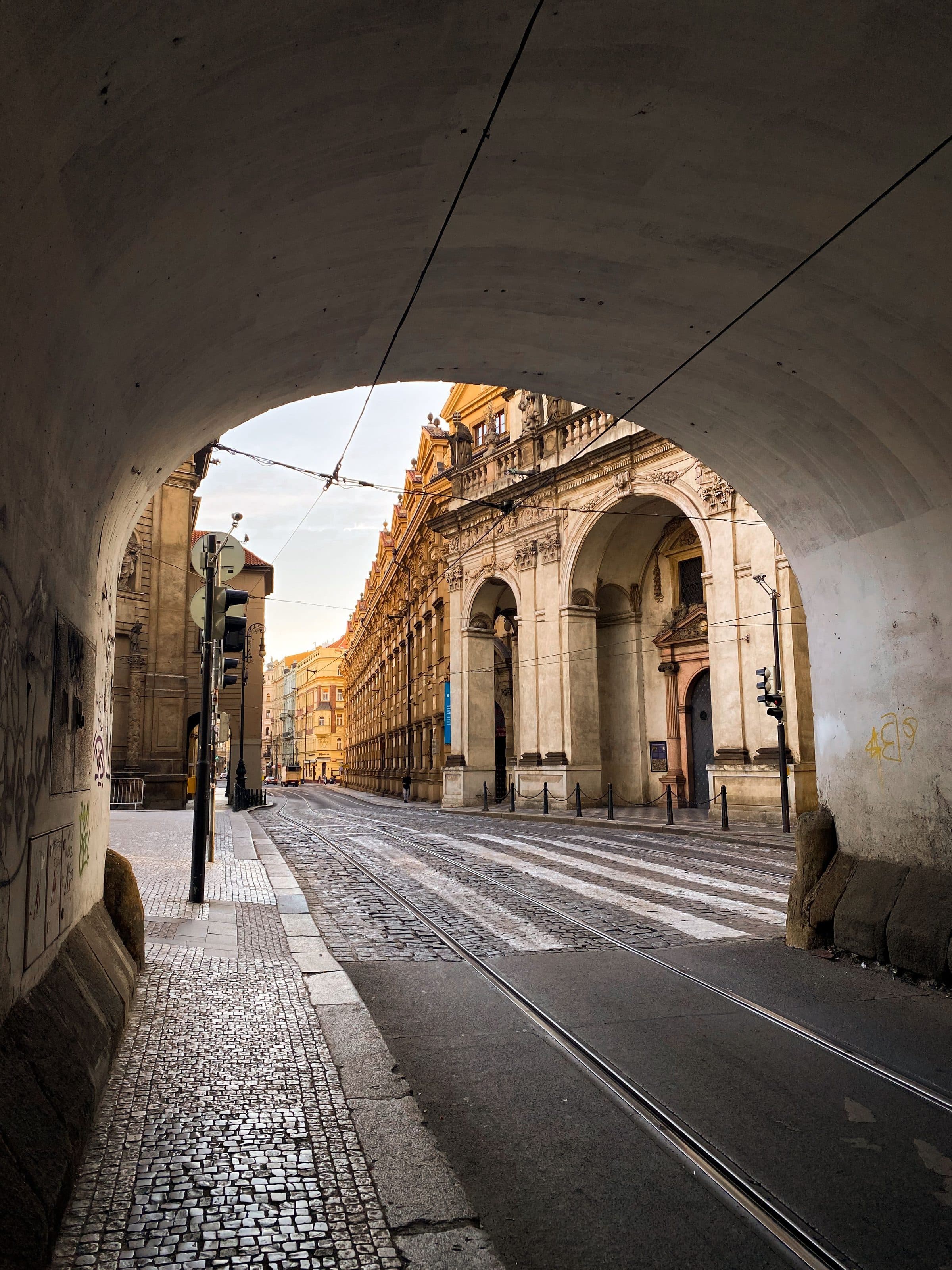Passagem sob arco que leva a uma rua histórica em Praga, na República Tcheca