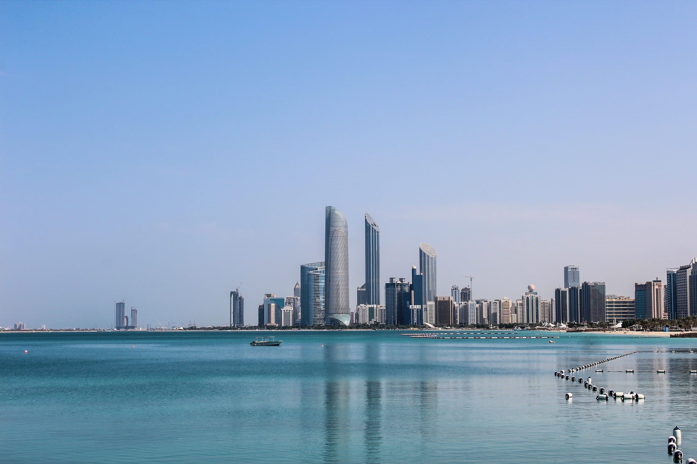 Skyline de Abu Dhabi refletido nas águas calmas do Golfo em um dia ensolarado