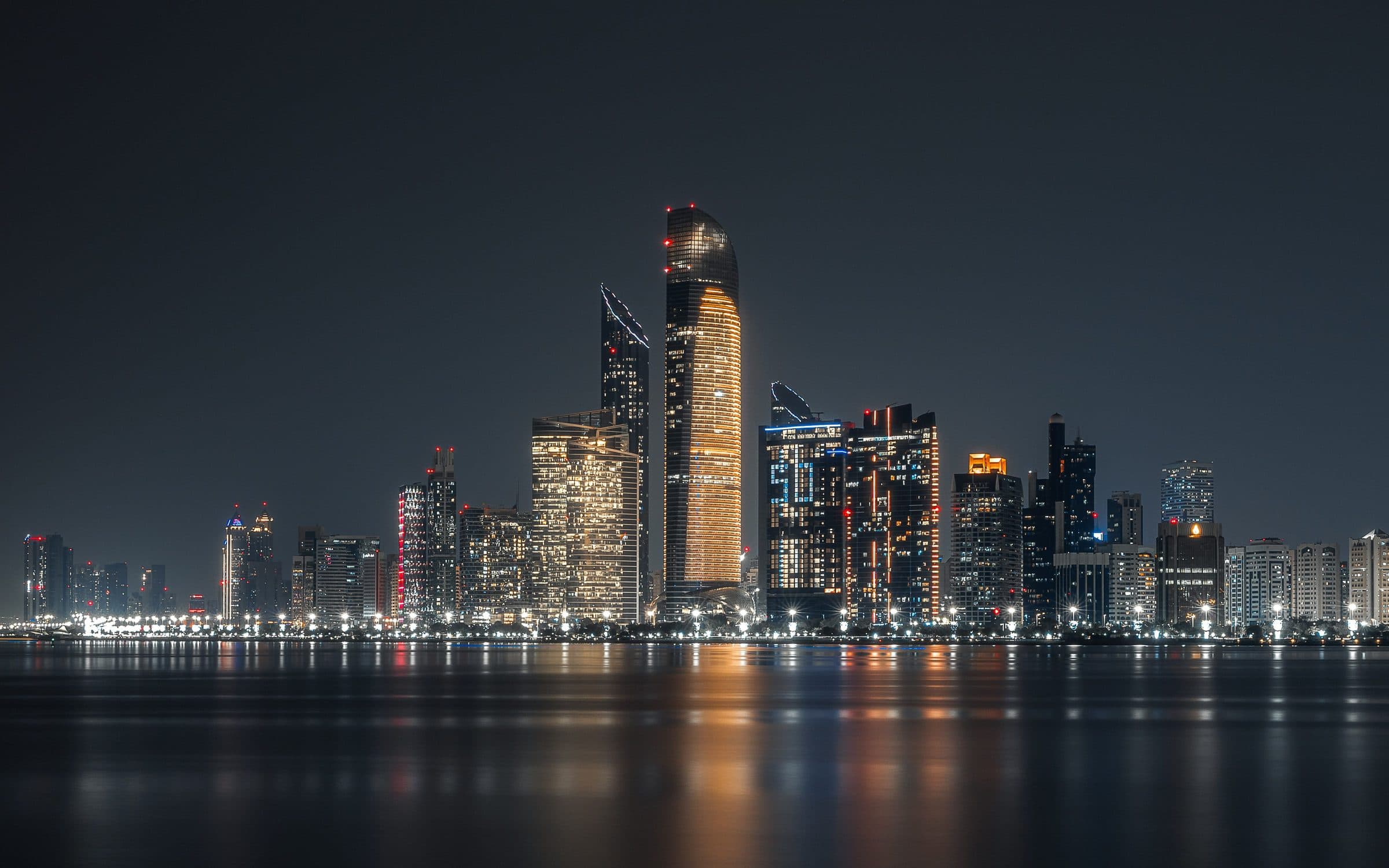 Arranha-céus iluminados de Abu Dhabi refletidos na água à noite