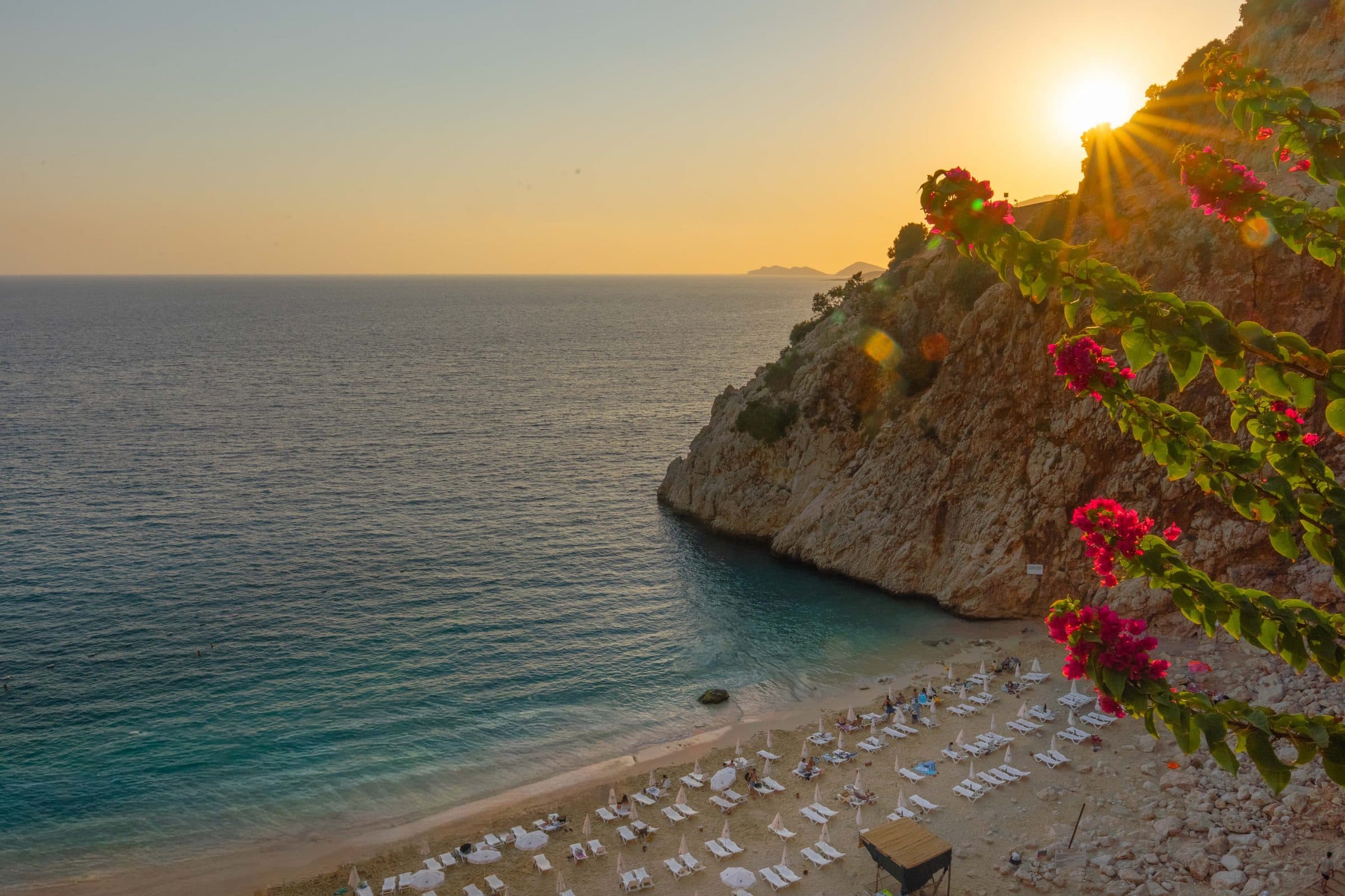 Pôr do sol na praia de Kaputas em Antalya com flores e mar calmo