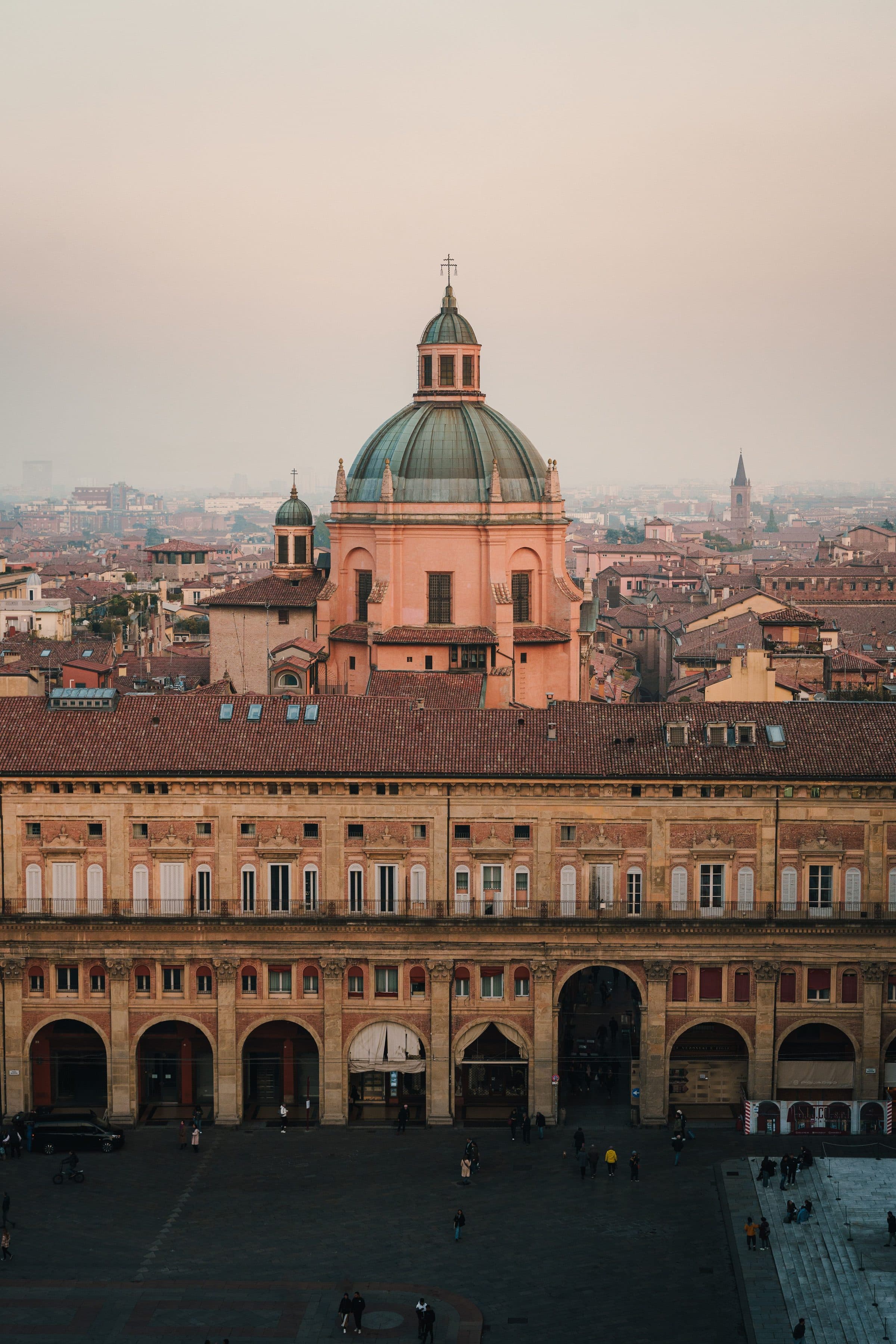 Vista dos edifícios históricos e cúpulas no horizonte de Bolonha durante o pôr do sol