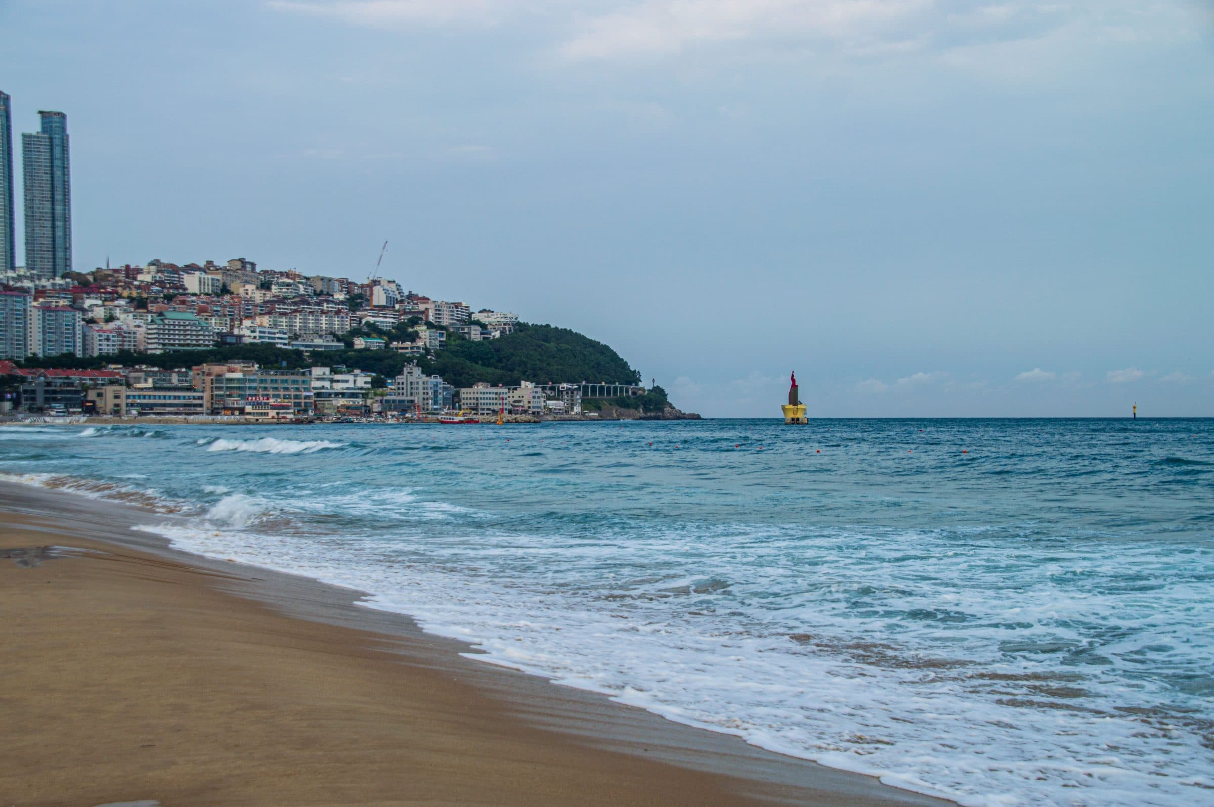 Vista da praia de Haeundae com o mar e os prédios da cidade ao fundo em Busan