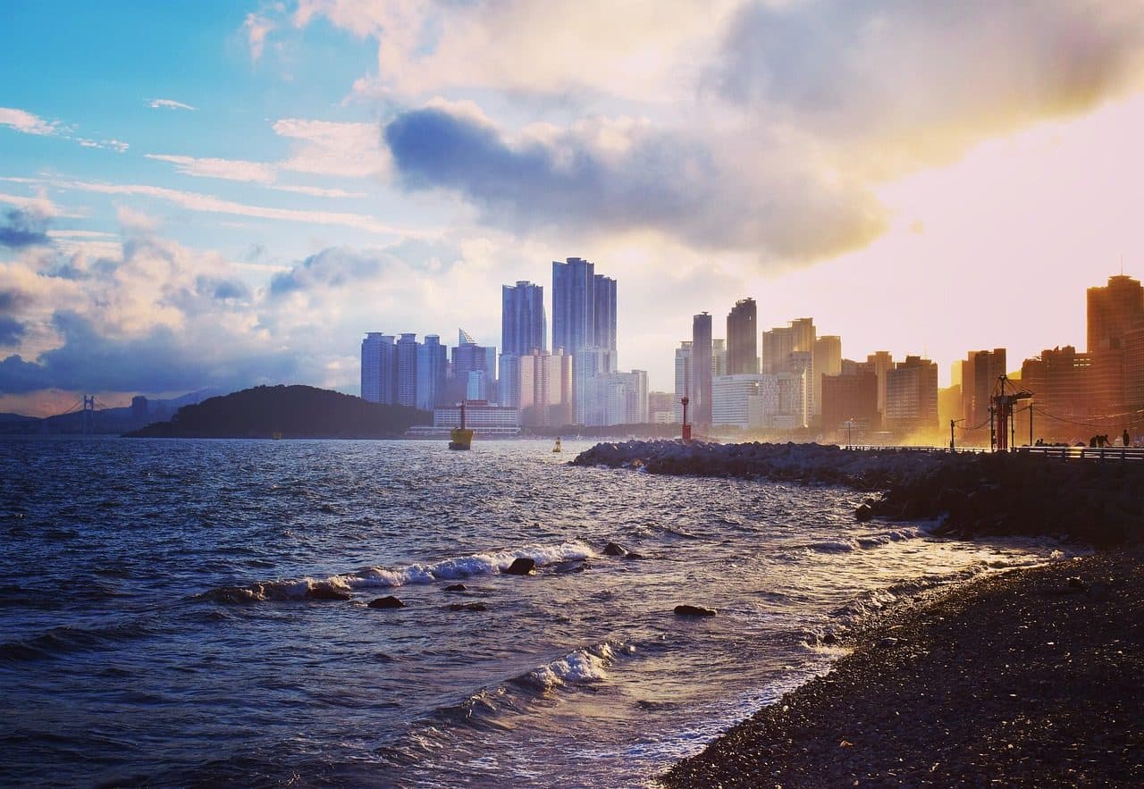 Pôr do sol na praia de Haeundae em Busan, com vista para o mar e a silhueta dos prédios da cidade