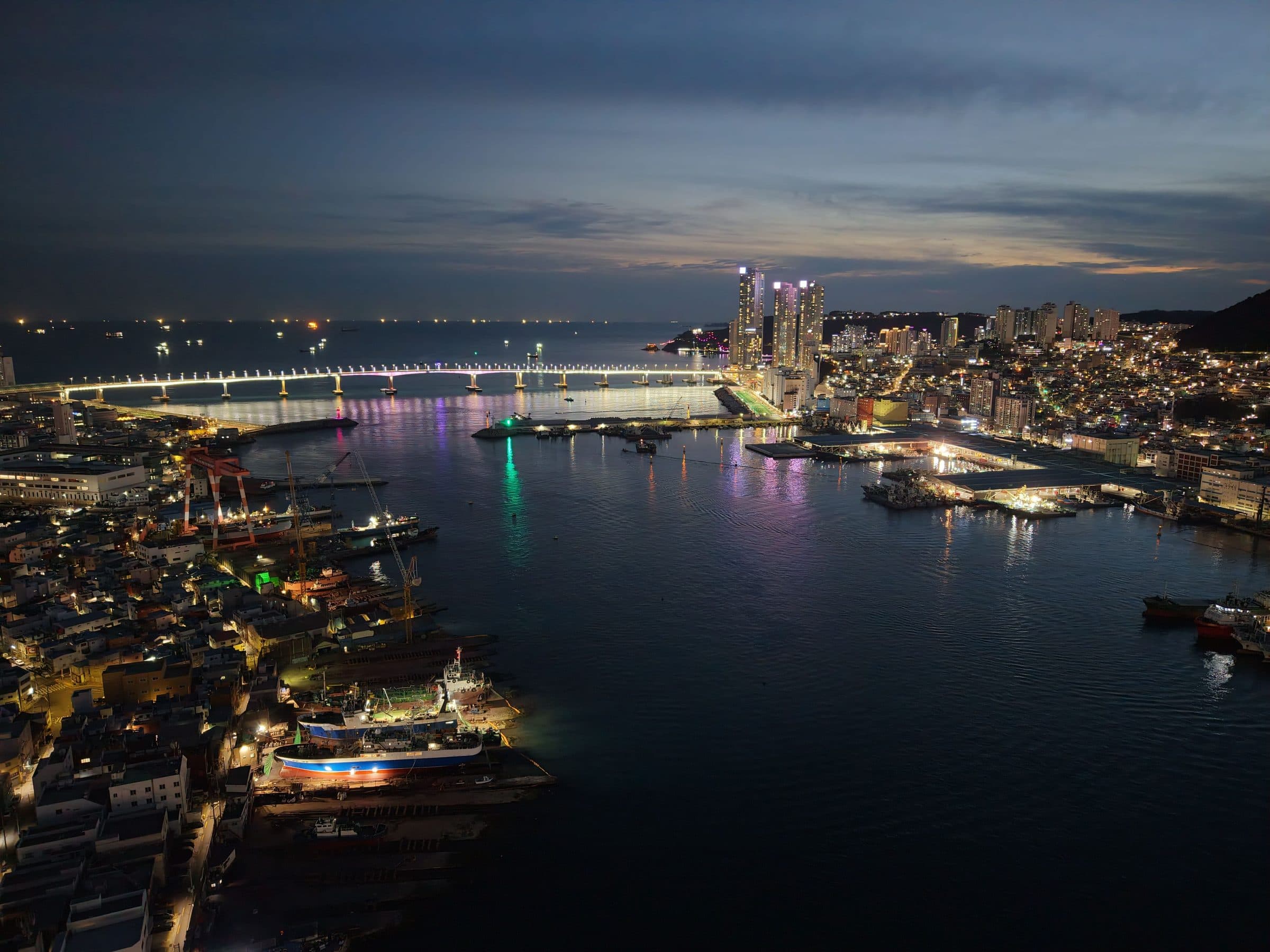 Vista aérea da Ponte Gwangan à noite em Busan com as luzes da cidade refletidas na água