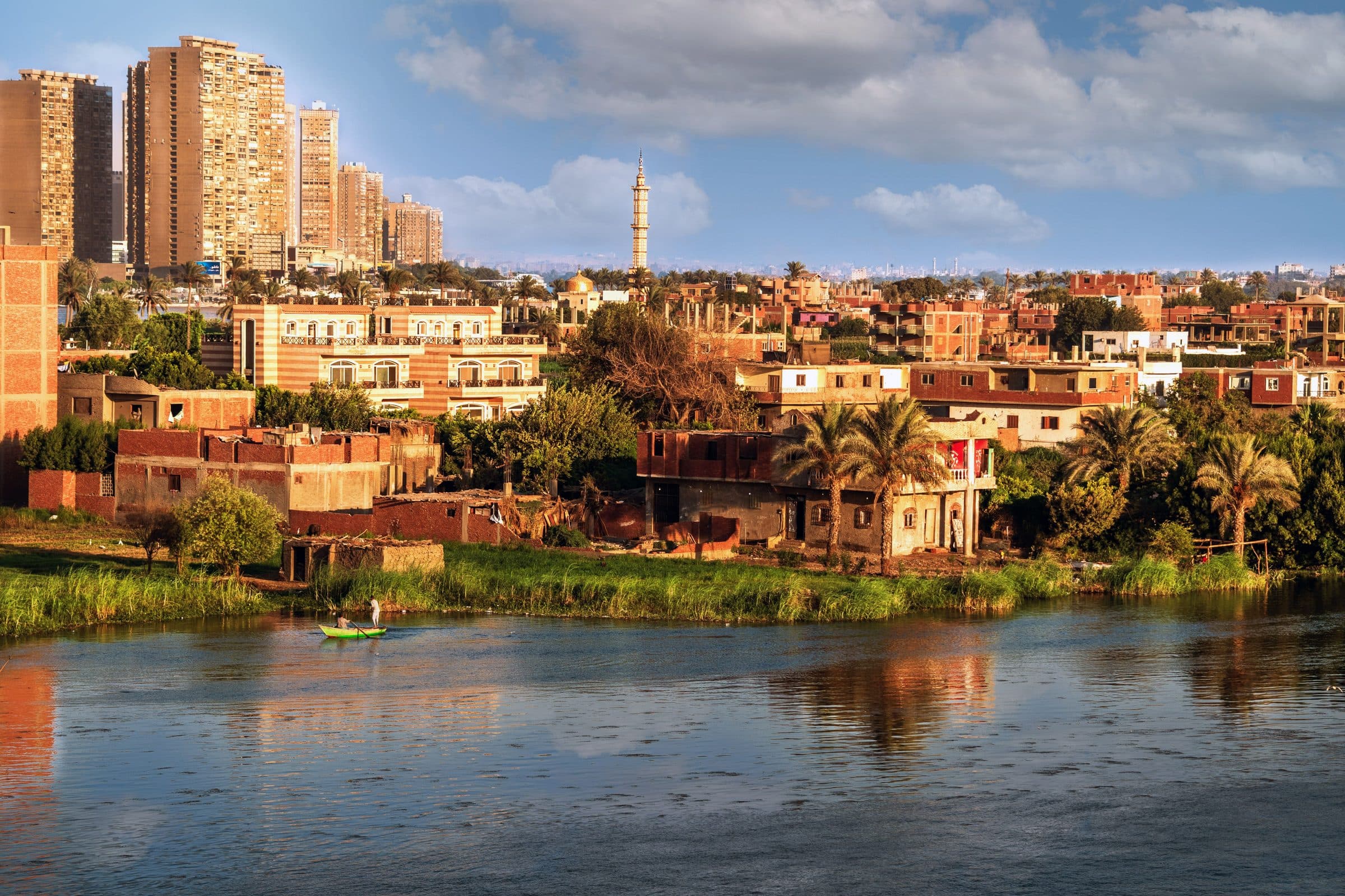 Paisagem urbana e rural com rio, edifícios e uma mesquita ao fundo