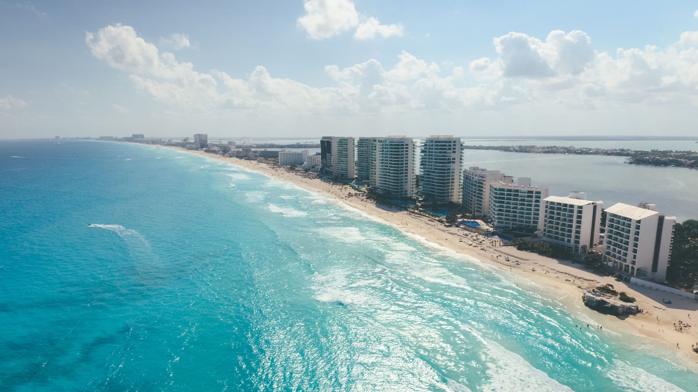 Vista aérea das praias de Cancún com resorts à beira-mar sob céu ensolarado