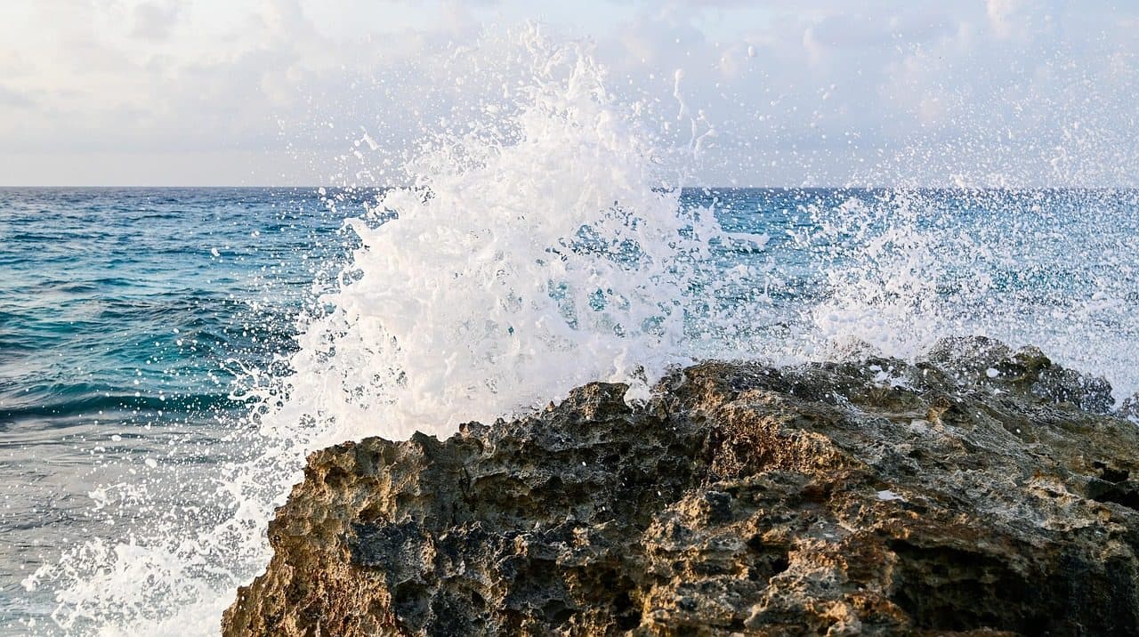 Praia em Cancún com ondas do Mar do Caribe quebrando nas rochas pela manhã